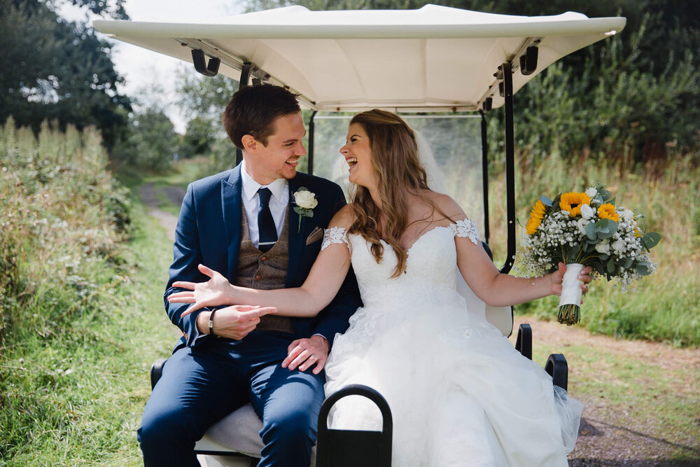 newly wedded couple jump straight into a golf club buggy