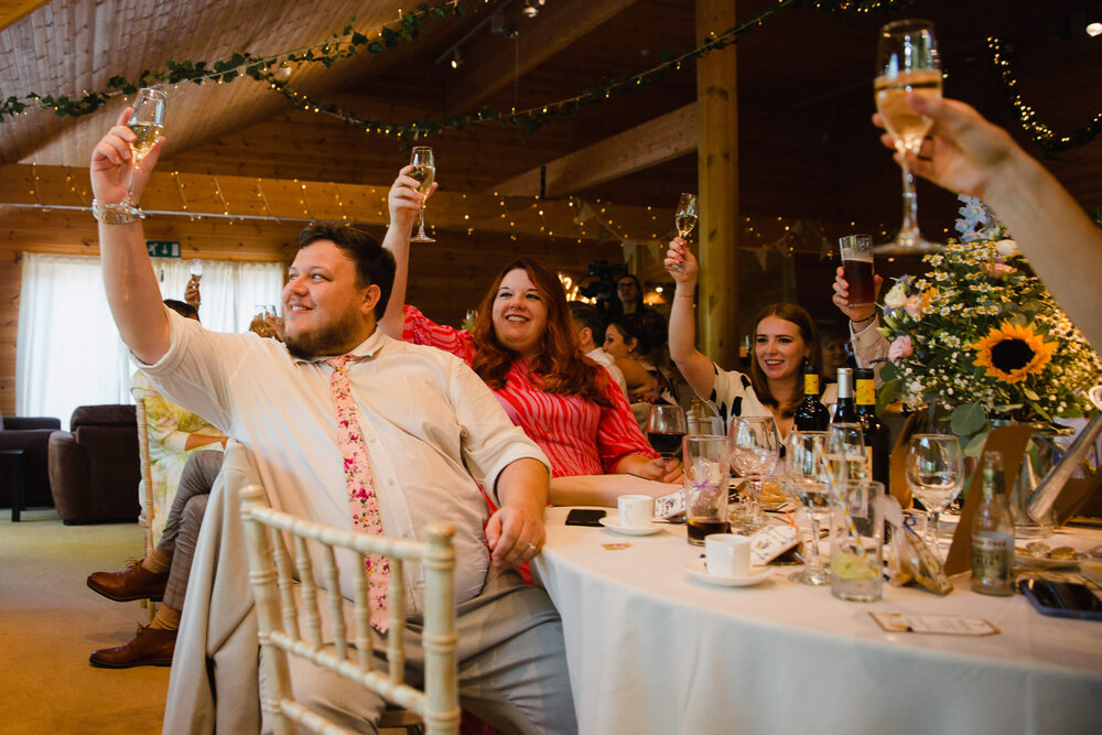 wedding guests raise their glasses into the air