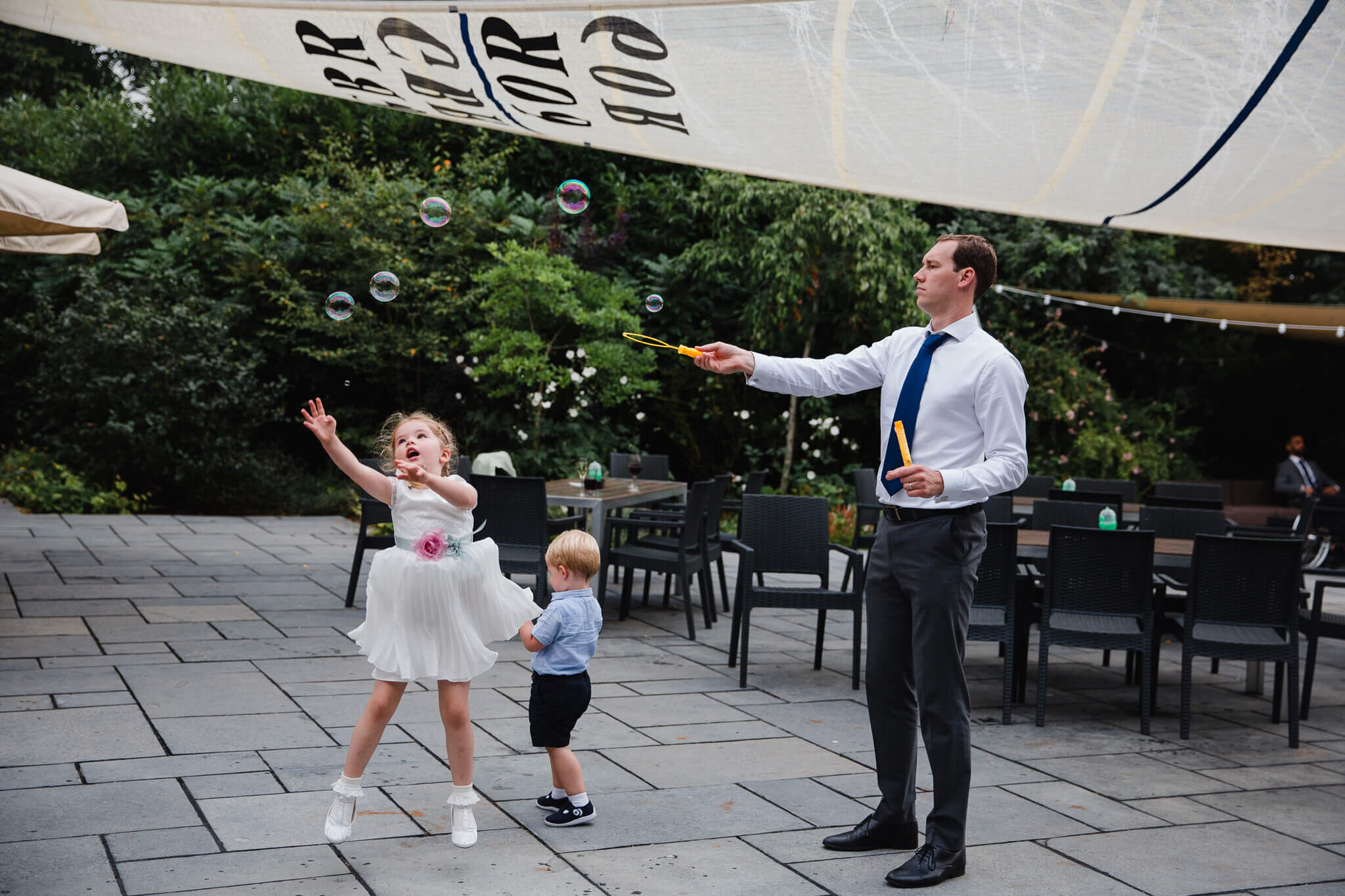 flower girl jumps in the air to catch bubbles
