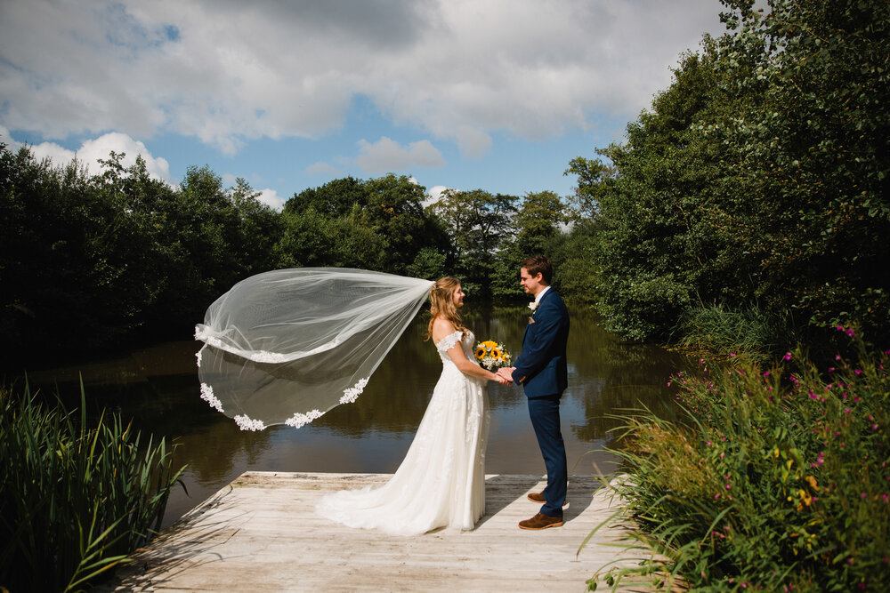 brides veil blows in the wind beside the lake