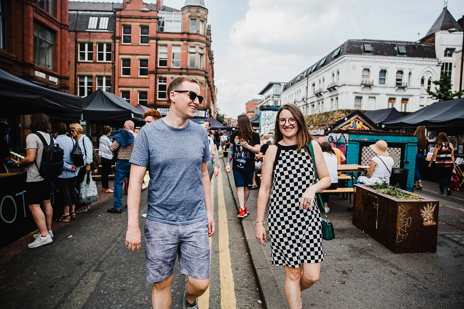 Candid couple walking through busy Stevenson Square market area in the Northern Quarter Manchester