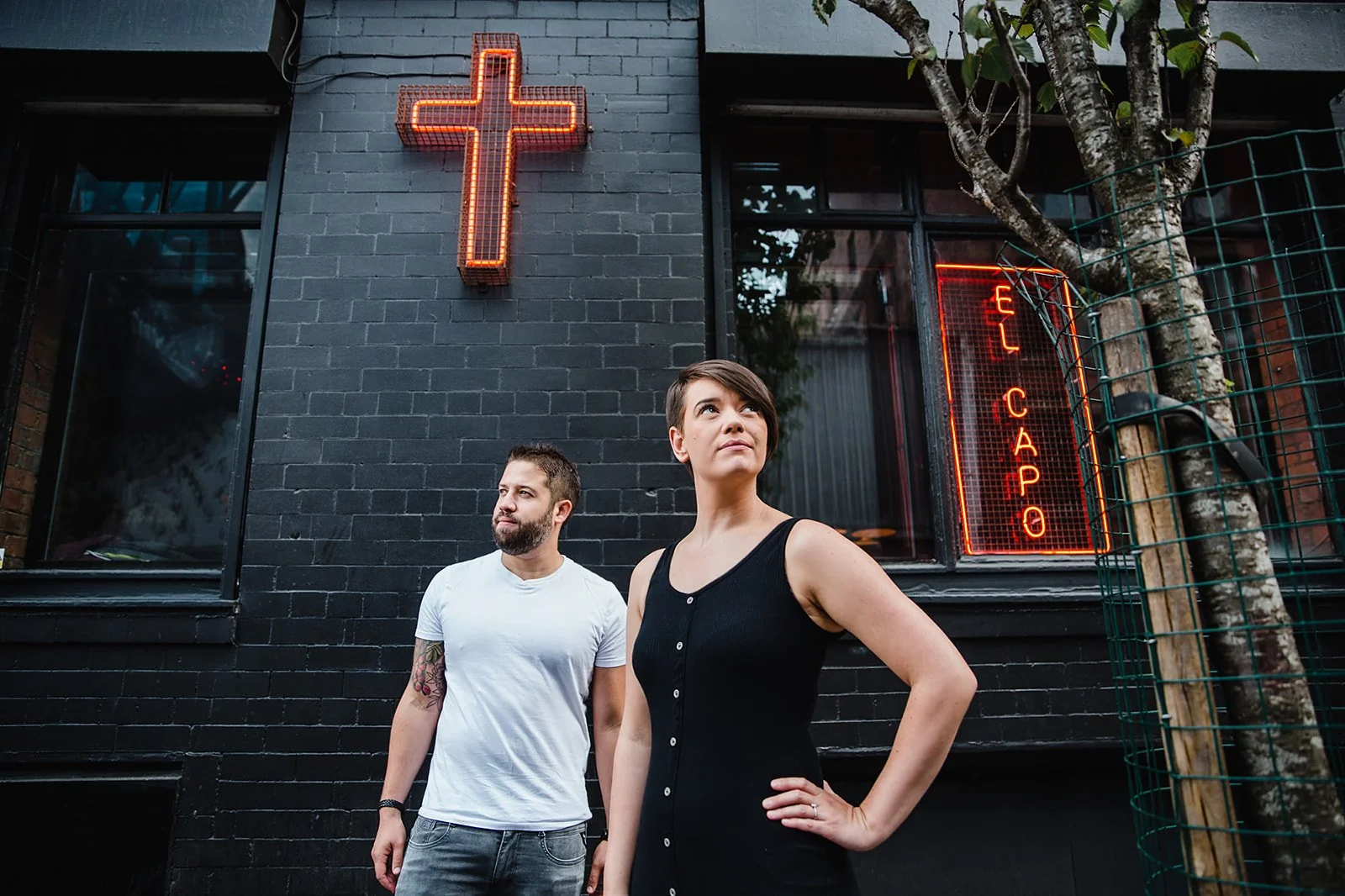 Couple standing outside El Capo with neon signage in Stevenson Square Northern Quarter Manchester