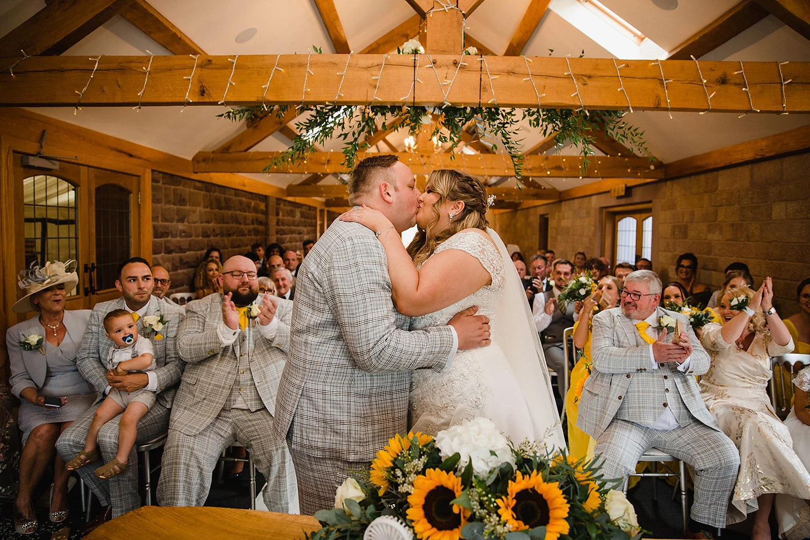 Bride and groom sharing their first kiss during their intimate indoor ceremony at Heaton House Farm.