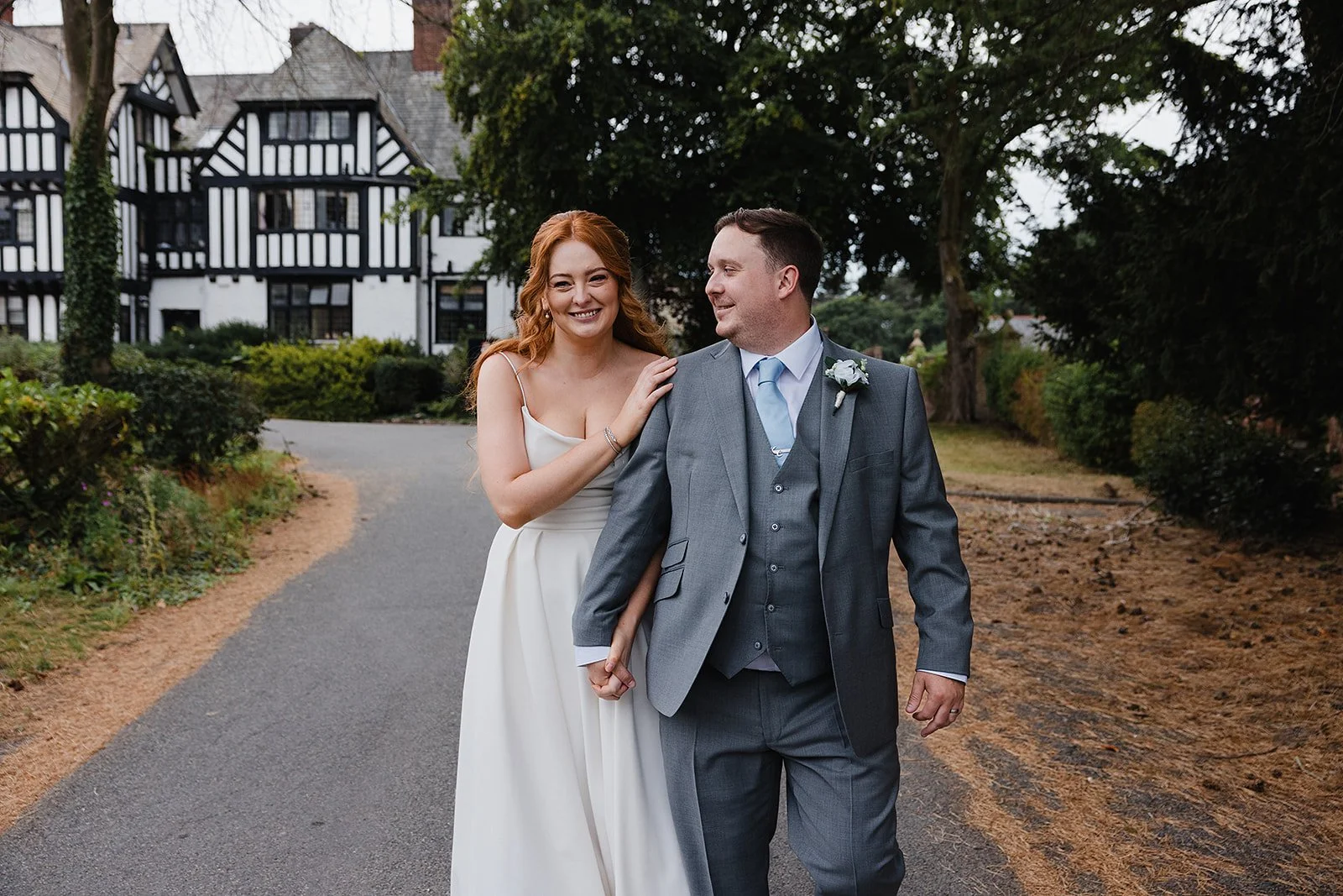 Newlyweds walking beneath the trees in the grounds of Inglewood Manor