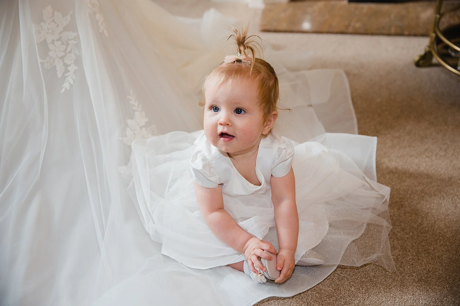 Baby sitting on the reception floor during relaxed wedding moments