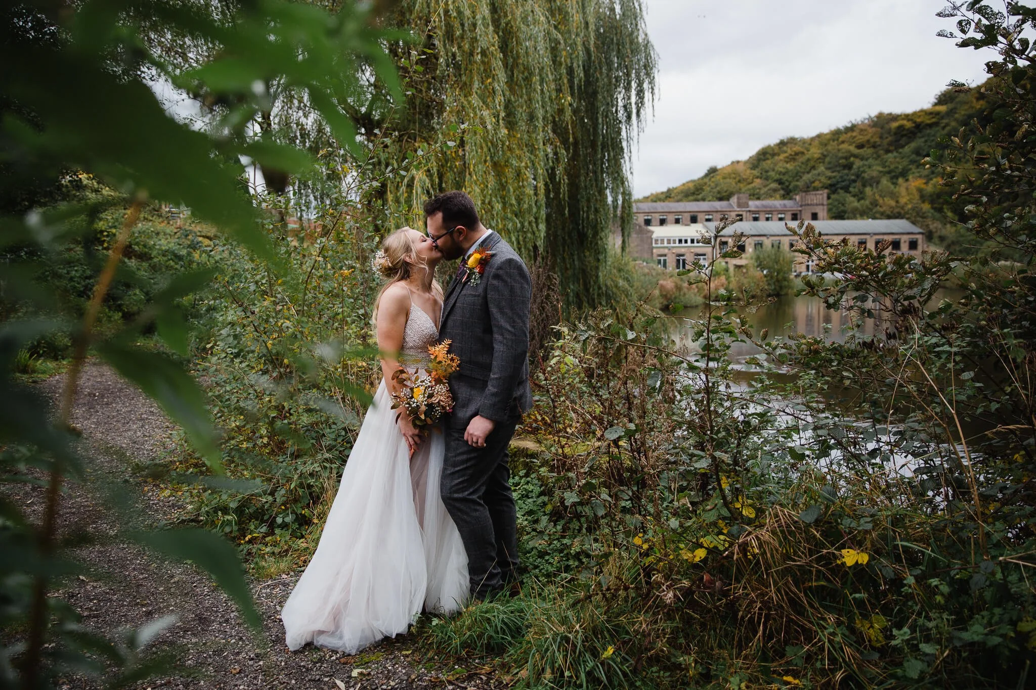 Bride and Groom Kissing with the Venue Halifax featuring in the landscape background