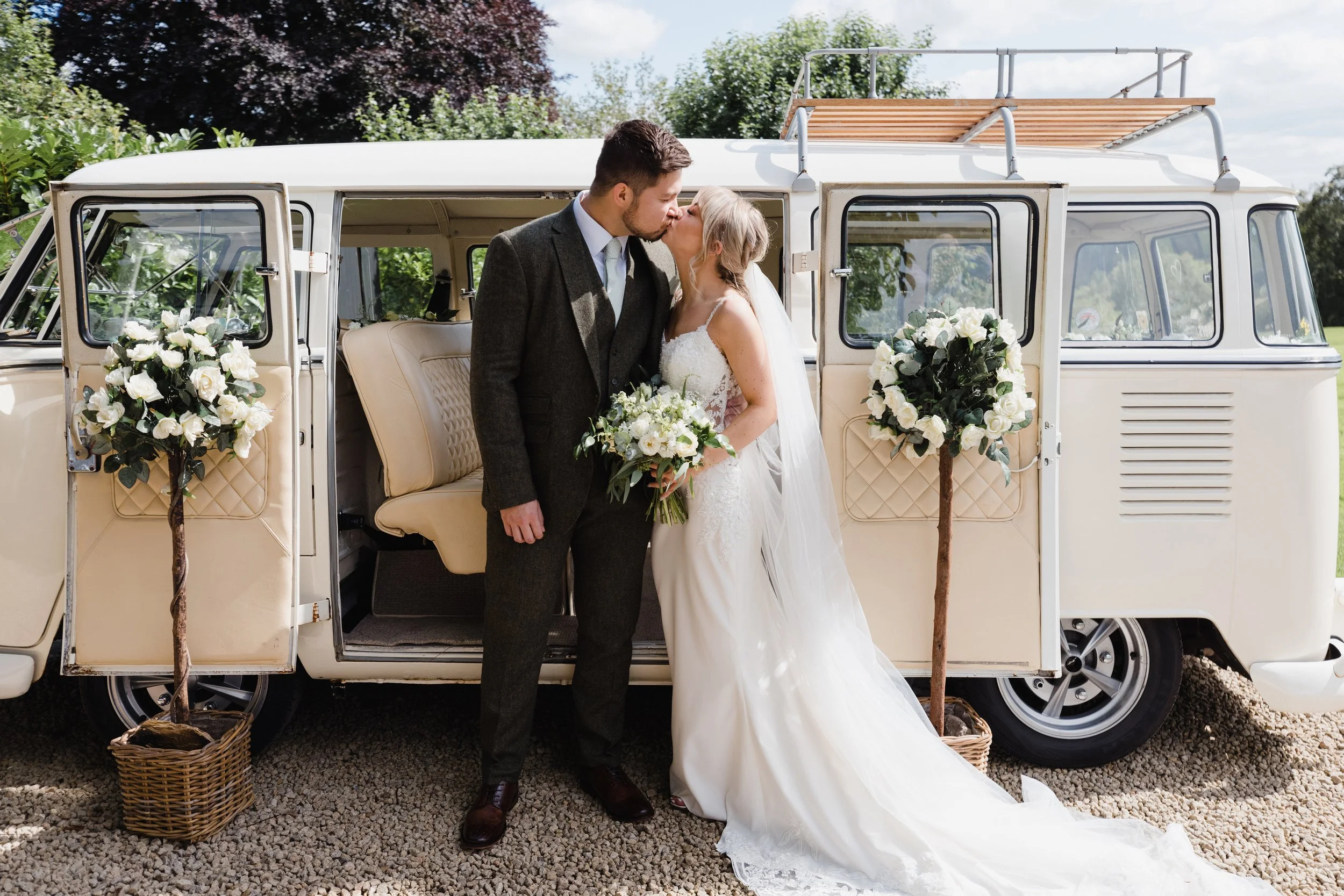 Rebecca and Ray sharing a kiss in front of the vintage VW campervan during their Hyde Bank Farm wedding photography.