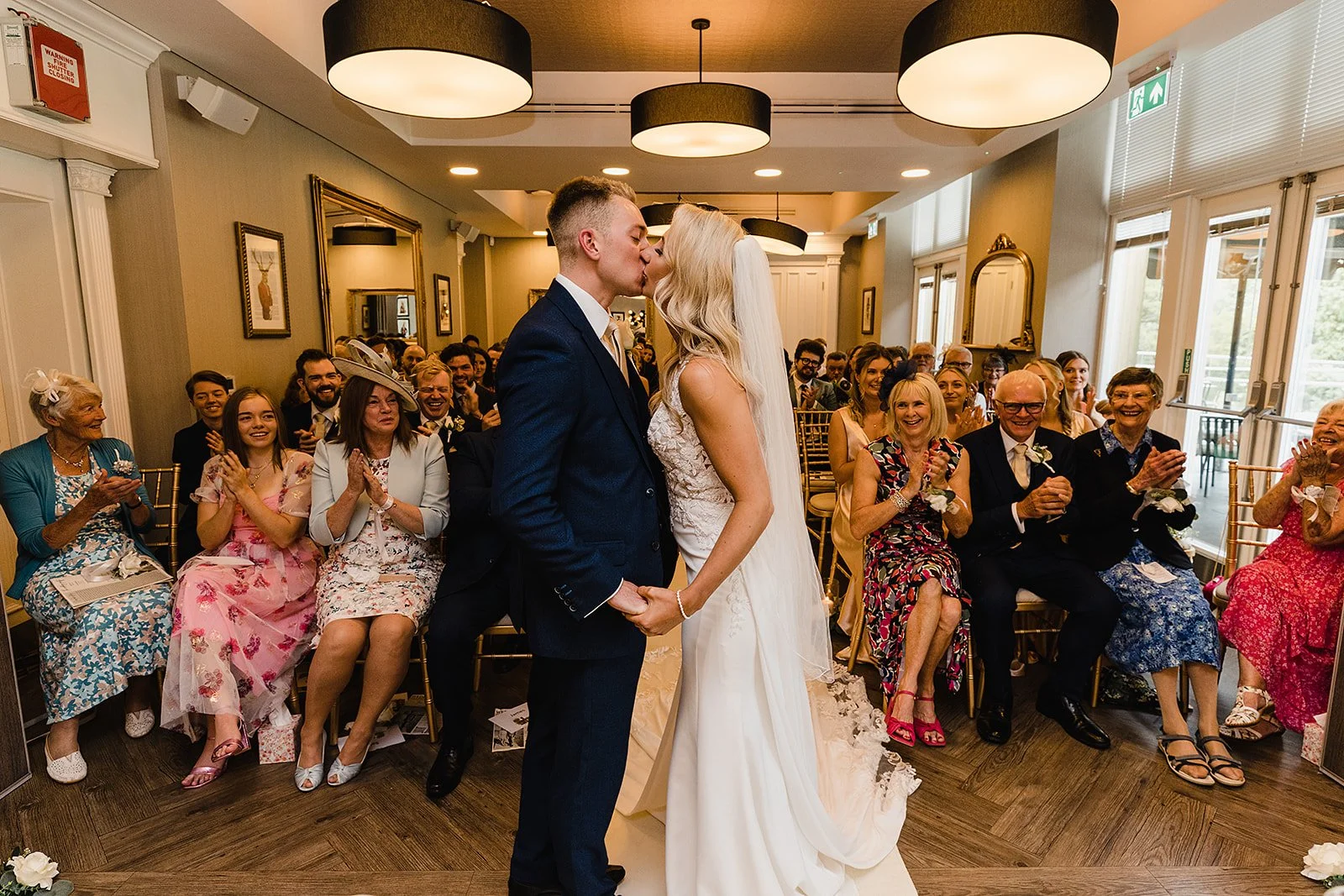 Michelle and Tom sharing their first kiss during their Oddfellows on the Park wedding, captured by a local Manchester photographer who knows the venue’s best spots.