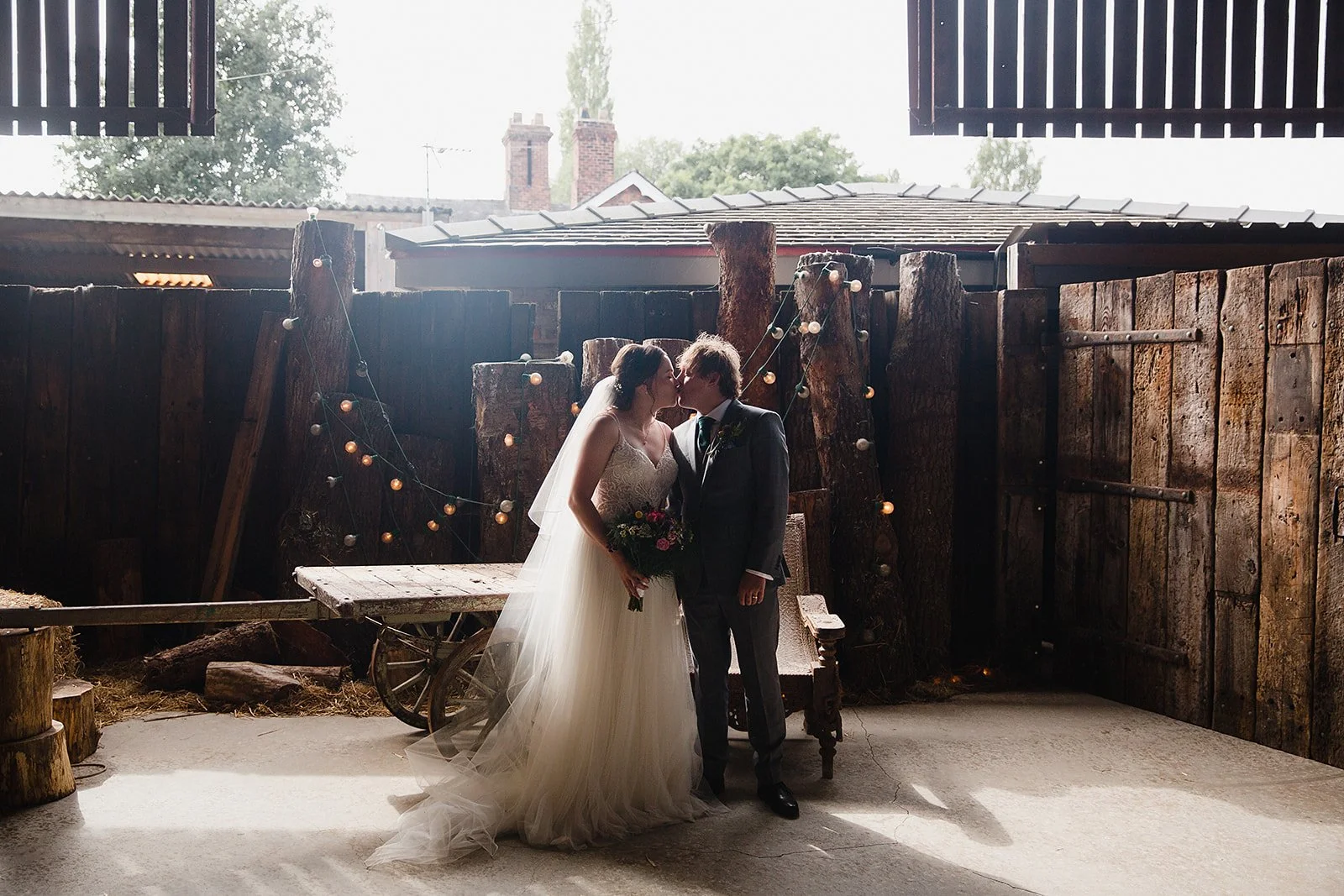 bride and groom kissing in the rustic barn doorway at Owen House Wedding Barn wedding photography