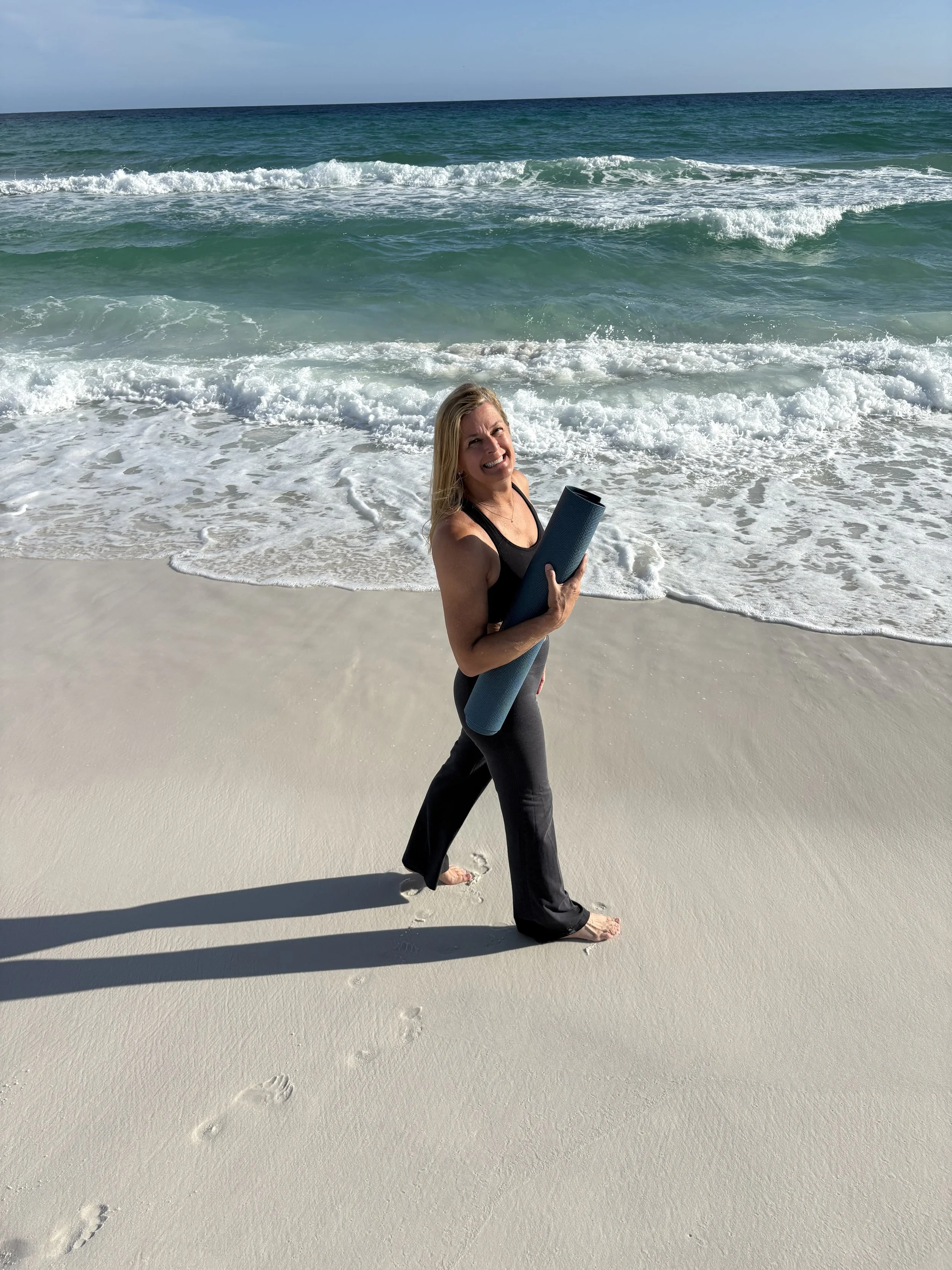 Wendy Methvin of HHI Yoga carrying a yoga mat on the beach in Hilton Head Island