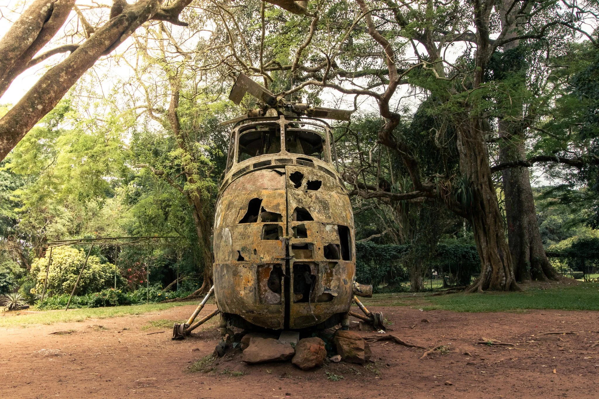 A rusty old military helicopter sits in the Aburi Botanical Gardens in Ghana, surrounded by lush greenery