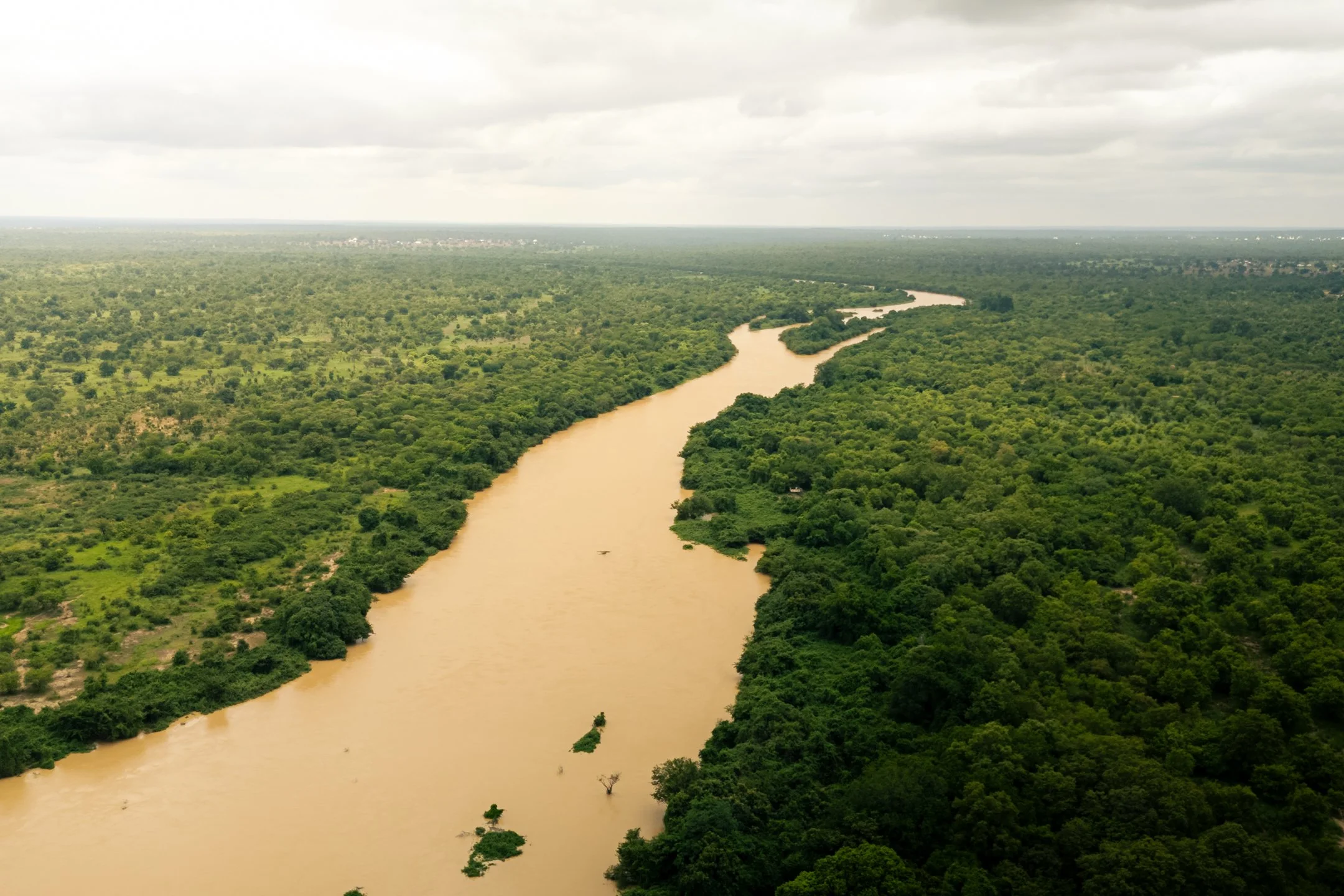 The muddy waters of the Black Volta River wind its way, separating Ghana and Burkina Faso in Upper West Region, Ghana