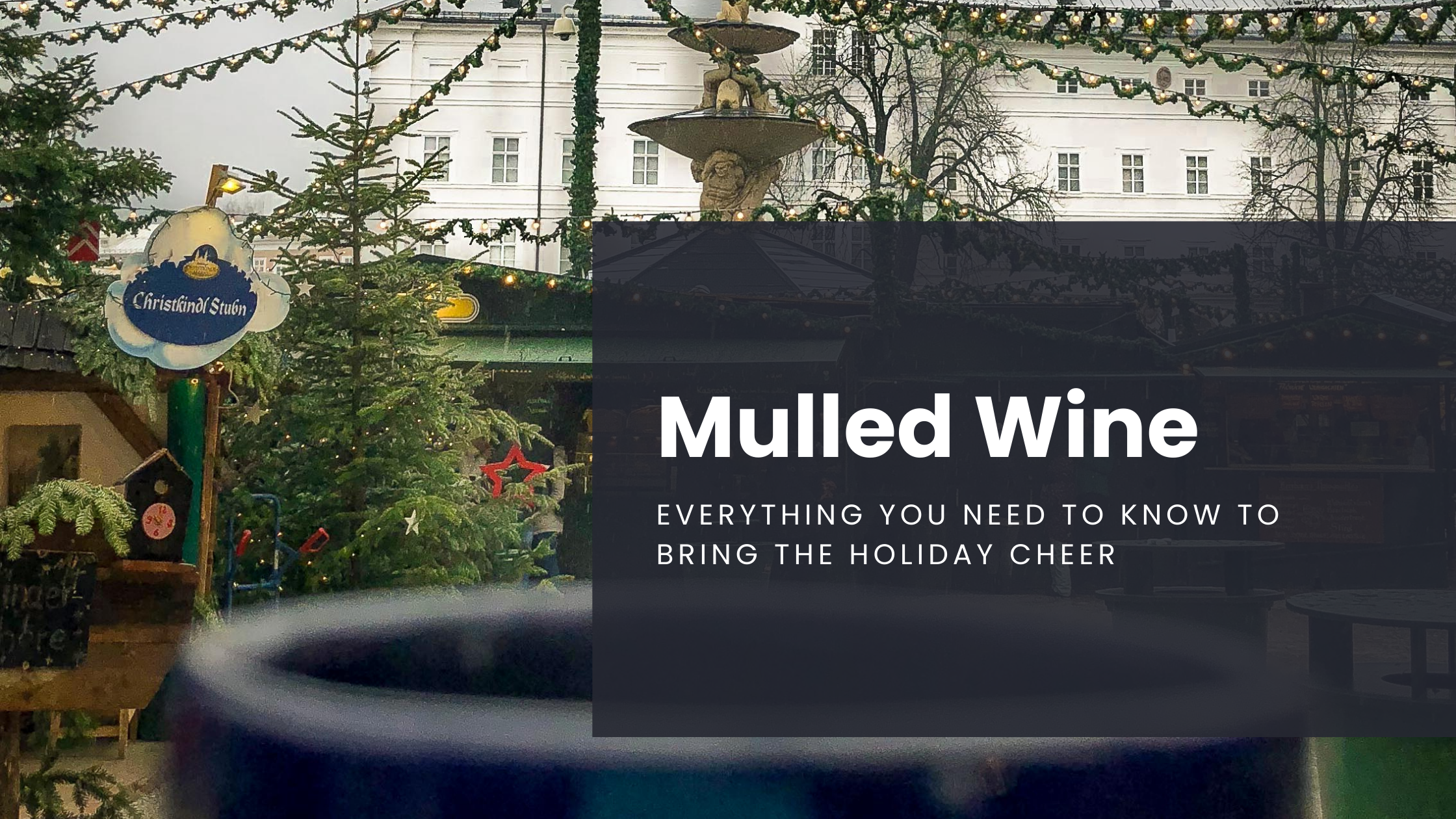 A glass of mulled wine is held in the foreground, enjoyed with a view of the Salzburg Christmas Market