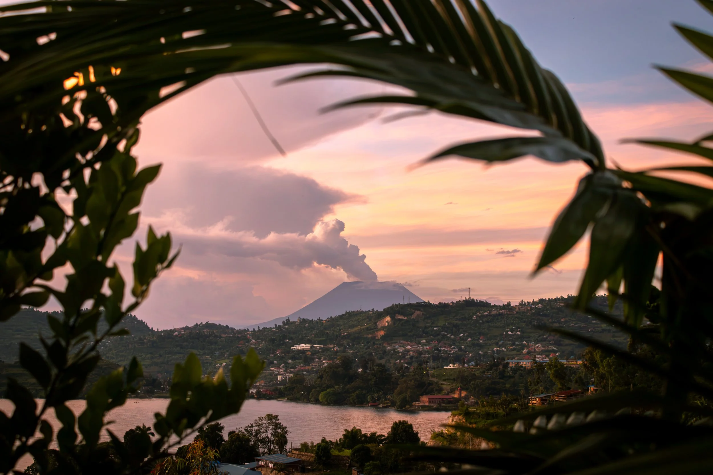 Mt. Nyiragongo, in the Democratic Republic of the Congo, spews smoke into the air with a pastel sunset, as seen from a garden in Rwanda