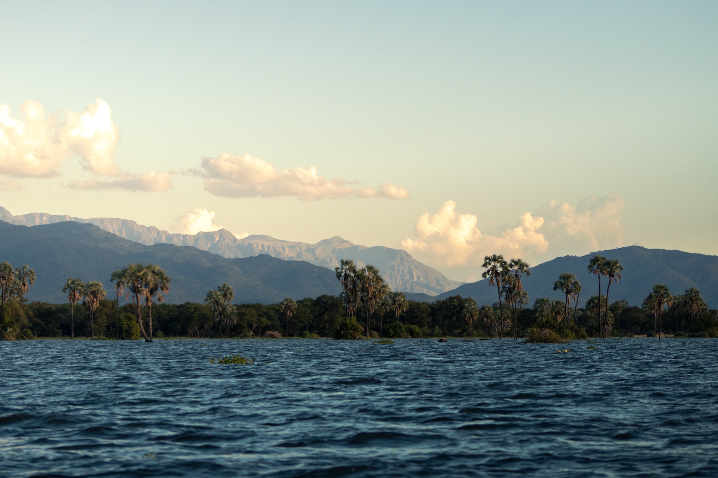 The sun paints the sky orange and illuminates the mountains along the flooded Shire River inside Liwonde National Park, Malawi