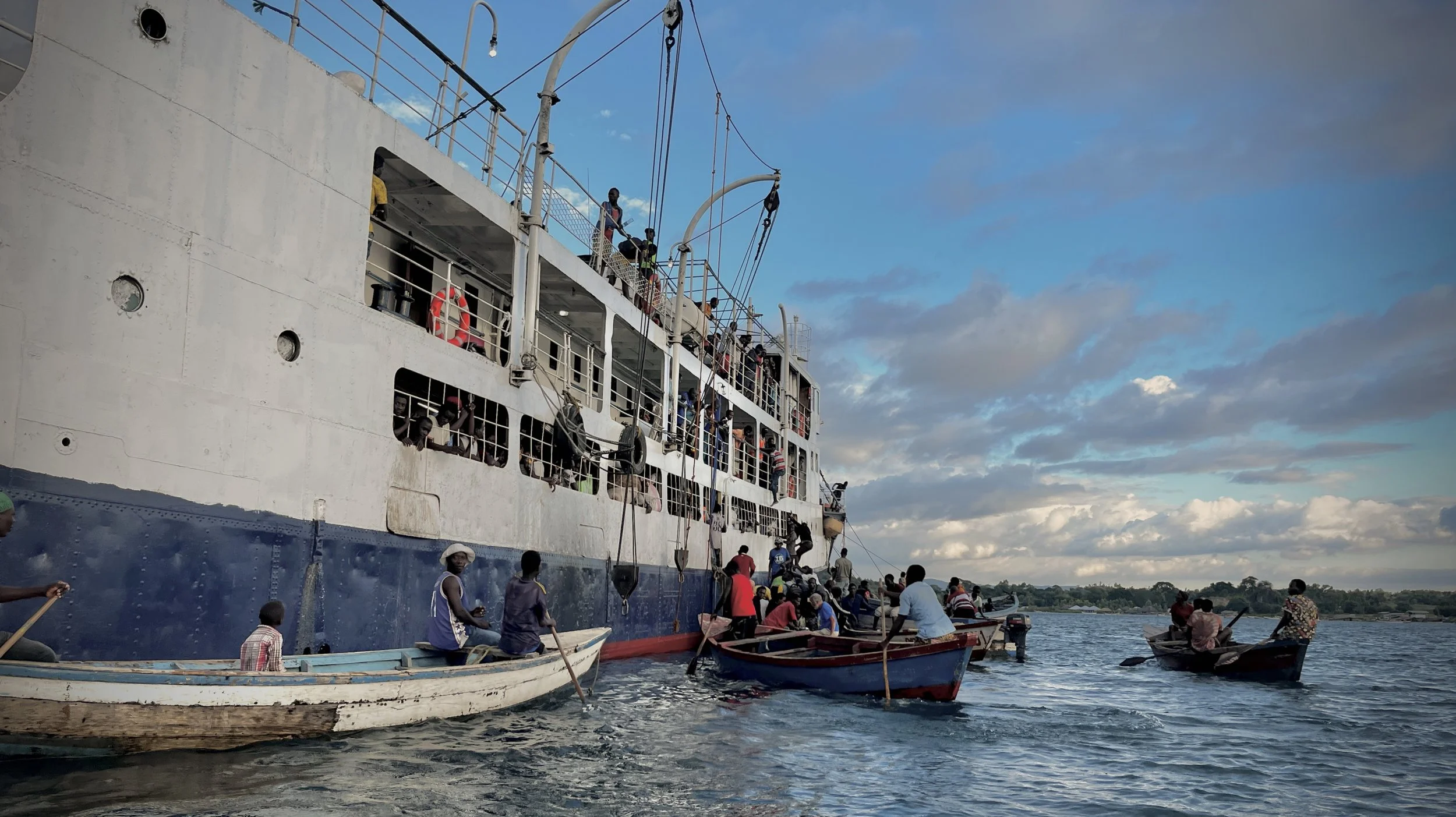 A crowd of passengers climb on and off the MV Ilala Ferry, jumping from the side of the ship and into awaiting fishing boats to get to shore