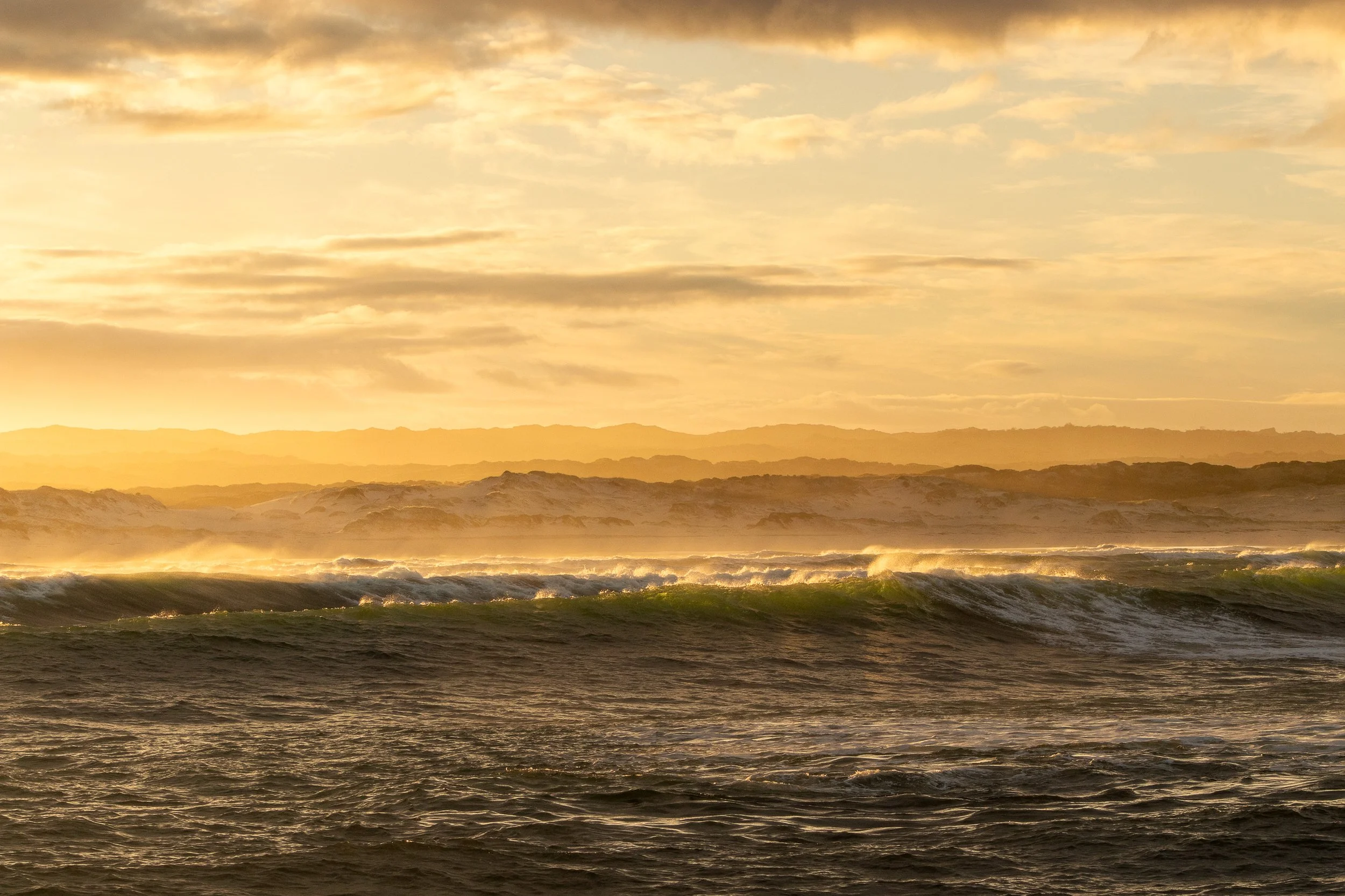 The orange sunrise illuminates the waters off the coast of Hermanus, South Africa