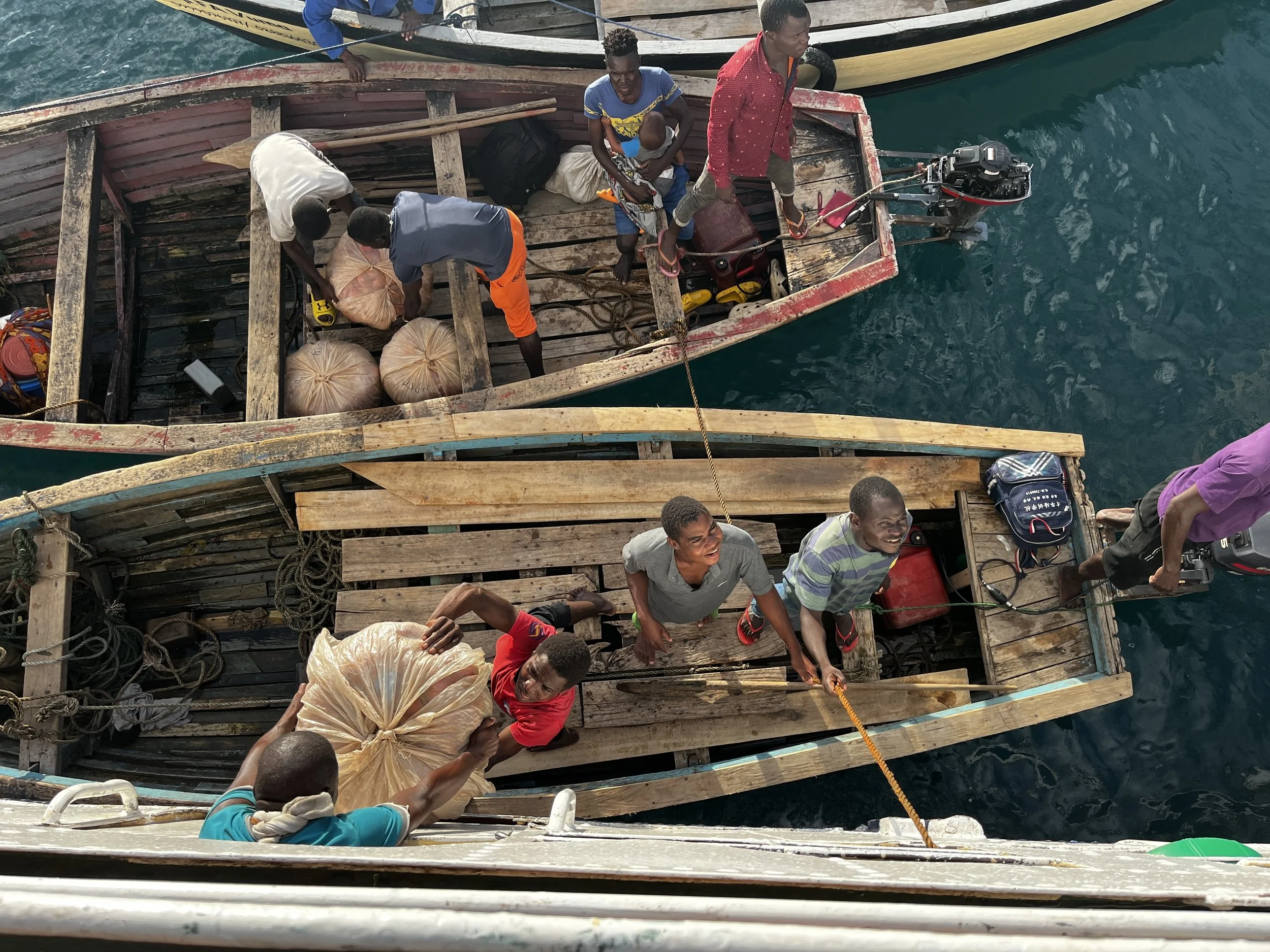 Two fishing boats and it's passengers help load both cargo and people off the MV Ilala Ferry in Malawi before shuttling back to shore