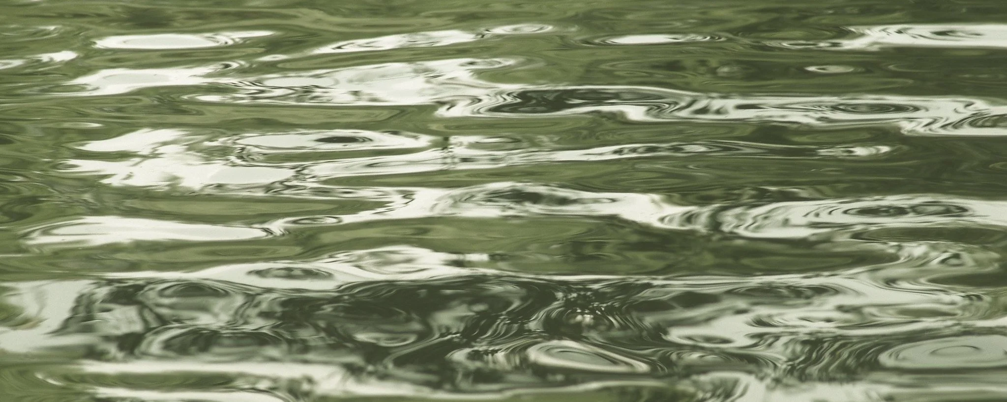 Wasseroberfläche mit sanften Wellen und Spiegelungen