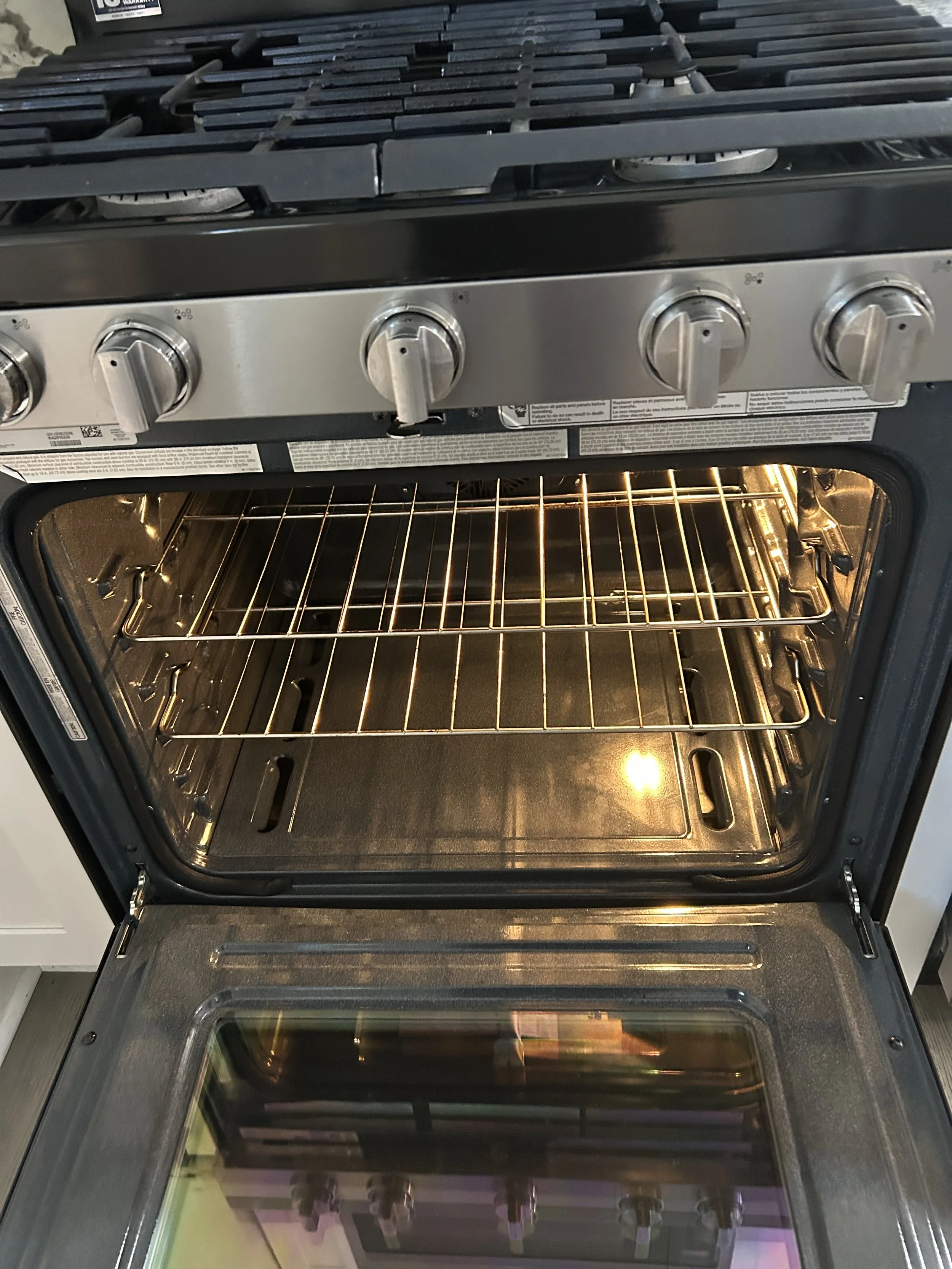 A black and stainless steel gas stove with four burners on top, control knobs in the front, and an oven with a glass window below.
