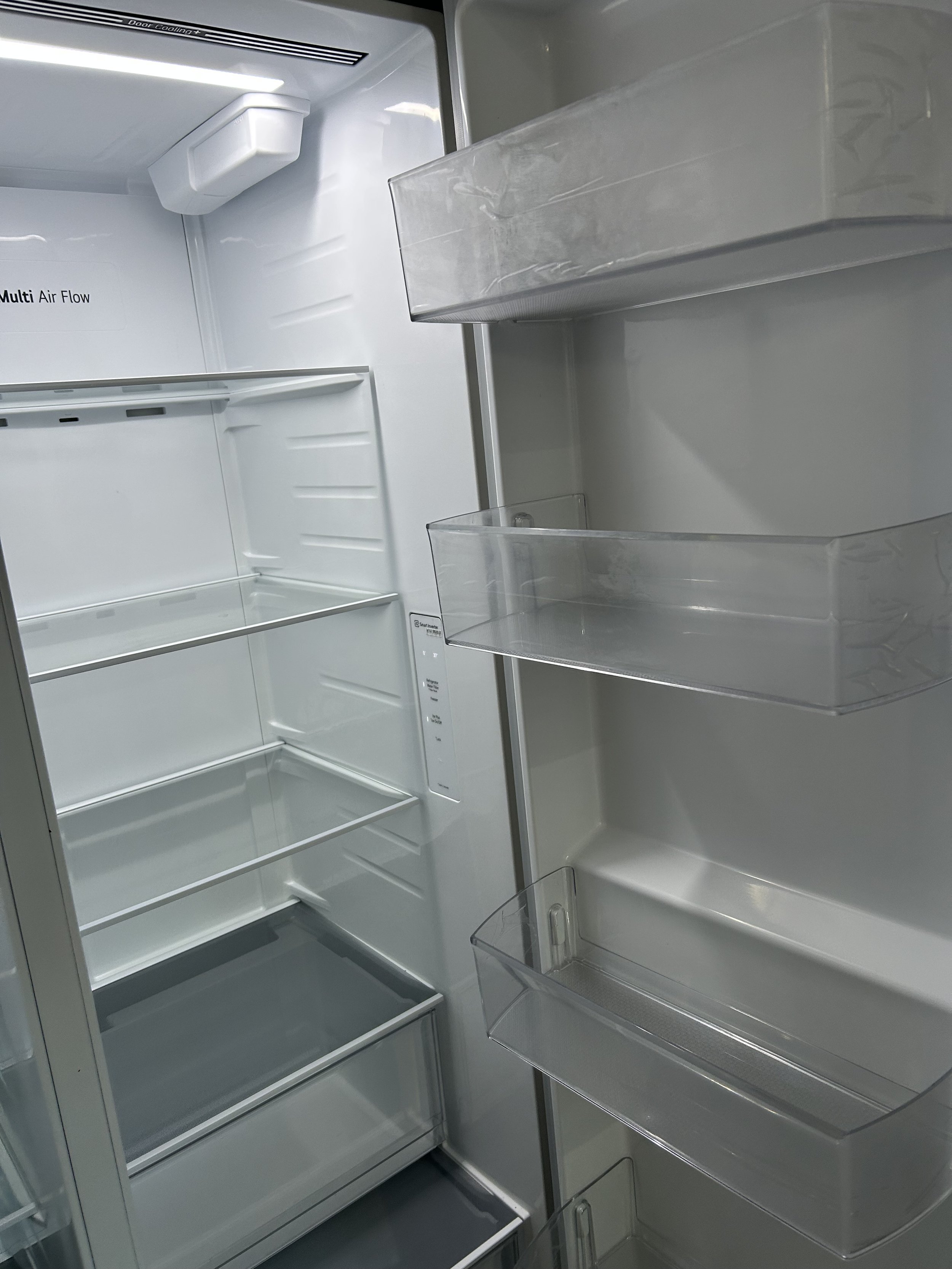 Inside an empty white refrigerator with glass shelves and door compartments.