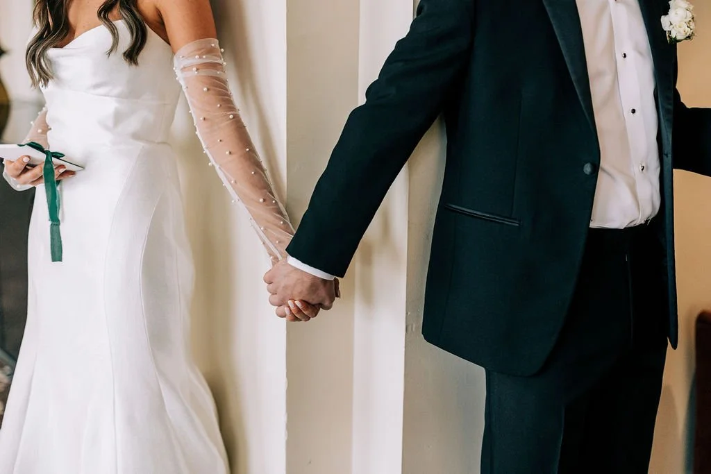 Bride and groom holding hands around a corner