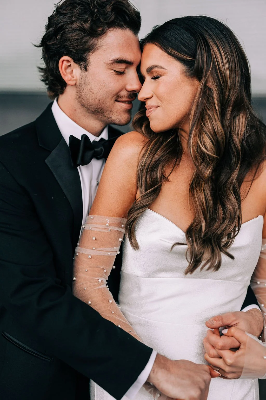 Bride and groom embracing, dressed in formal wedding attire.