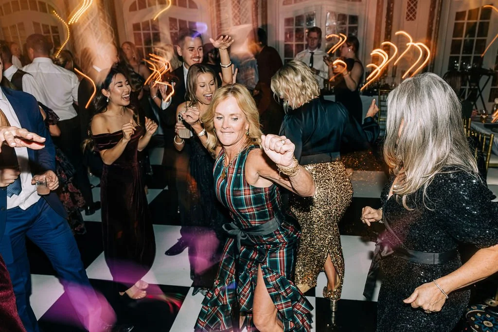 Group of people dancing at a party on a black and white checkered floor.