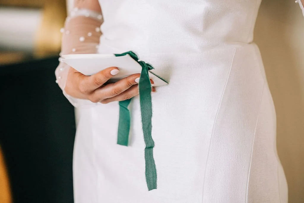 Close-up of person holding white tablet with green ribbon