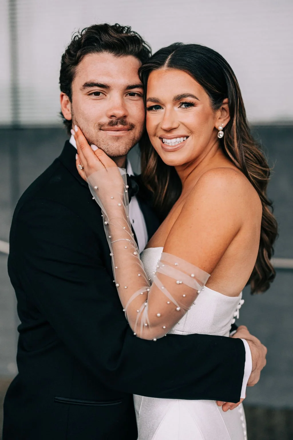 Couple embracing in formal attire, woman wearing a white dress.