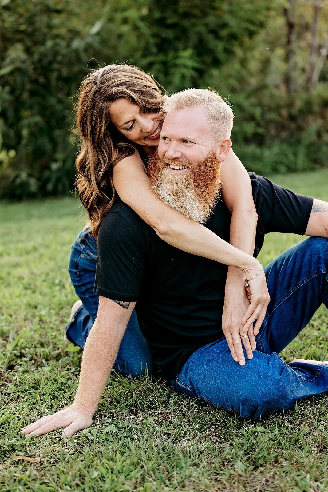 Couple smiling and embracing outdoors on grass