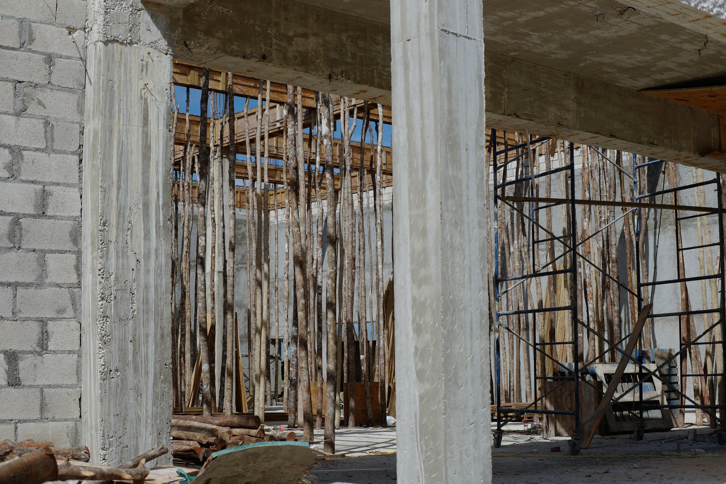 Construction site in Belize using locally cut sapling trees as concrete form supports