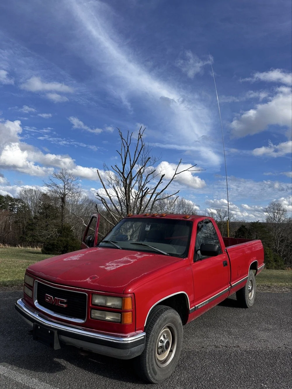 Red Chevrolet pickup truck with telescoping vertical antenna on the receiver hitch mount at us-2169