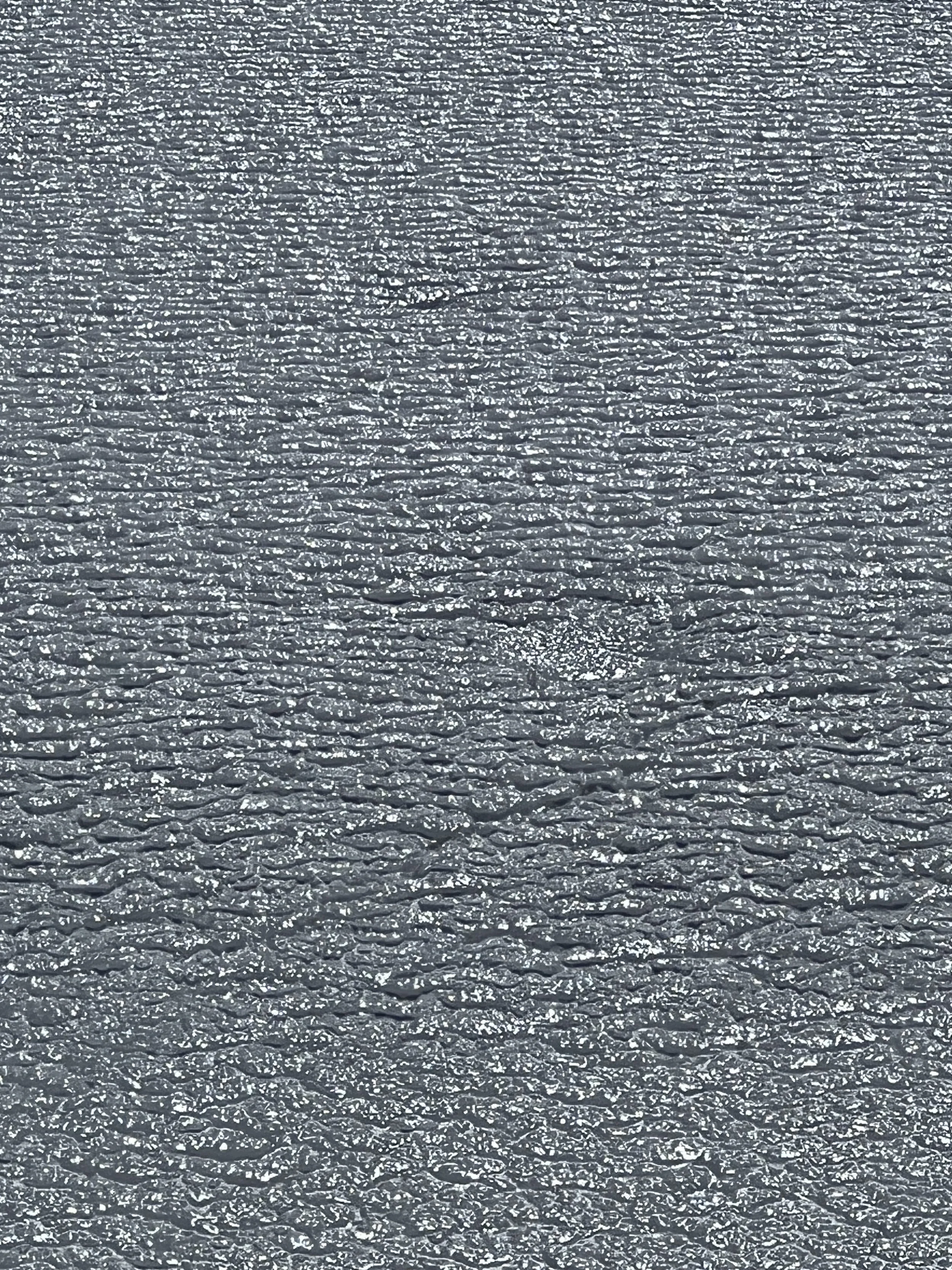 Close-up of a body of water covered in ice  with ripples and reflections of sunlight.