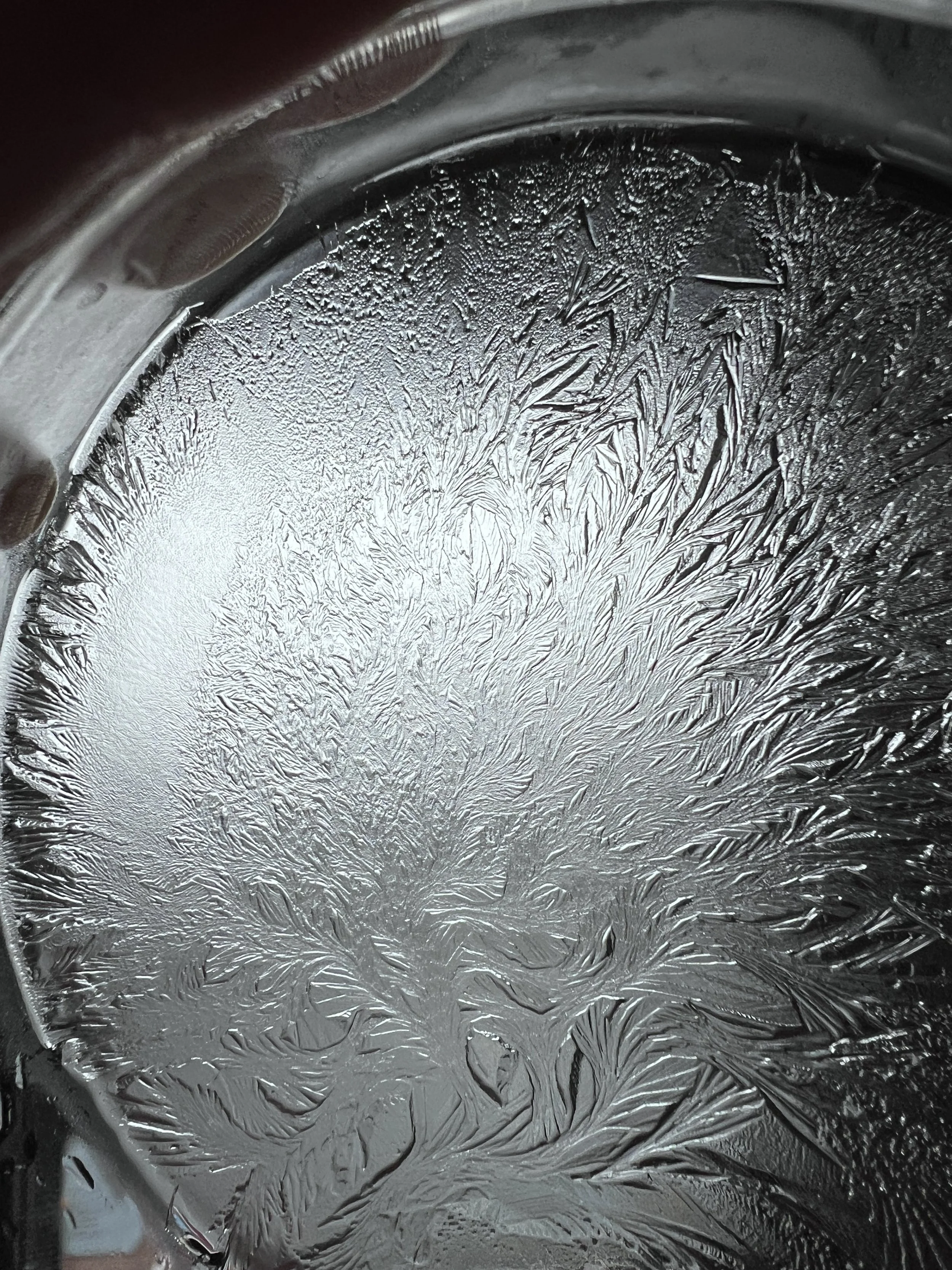 Close-up of a metallic surface with intricate frost patterns.