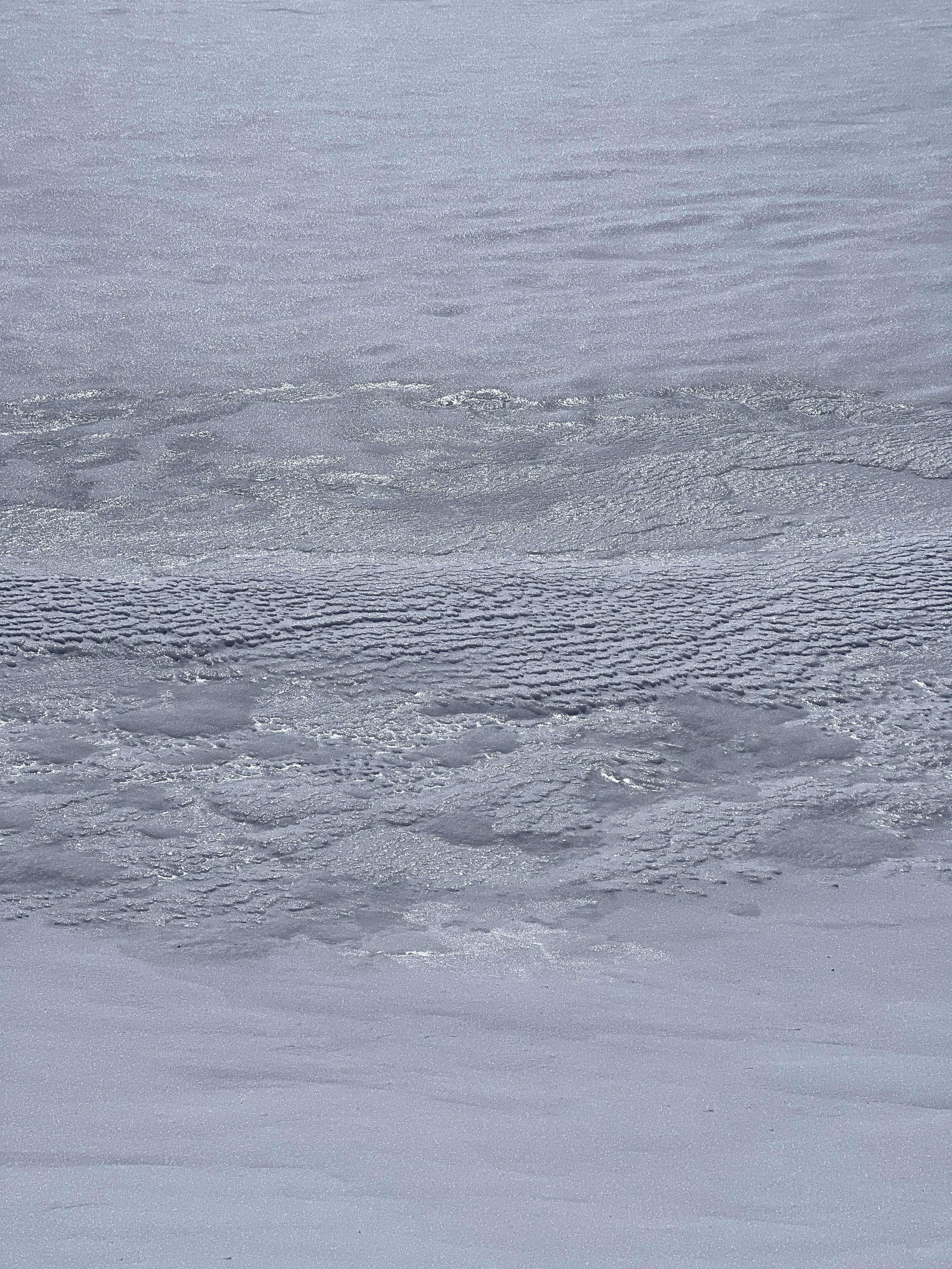 Close-up of a snow-covered surface with textured patterns and light reflections.