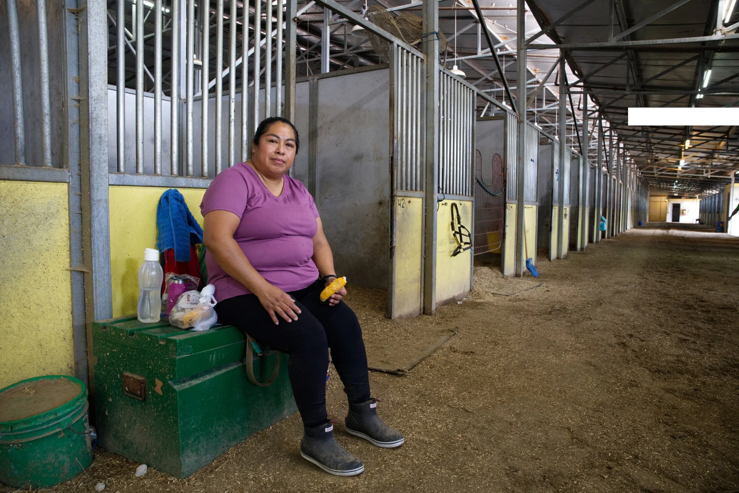  Sara se sienta en un contenedor de almacenamiento para descansar un momento y almorzar rápido después de caminar y bañar a varios caballos en el Hawthorne Race Course , Stickney, Illinois, cerca de Cicero, el 28 de agosto de 2026. Un paseador de cab