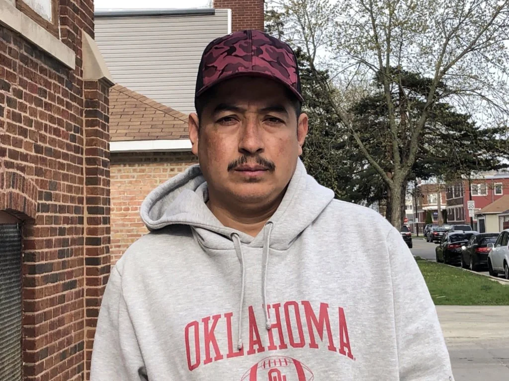 A man in a gray sweatshirt with a red baseball cap.