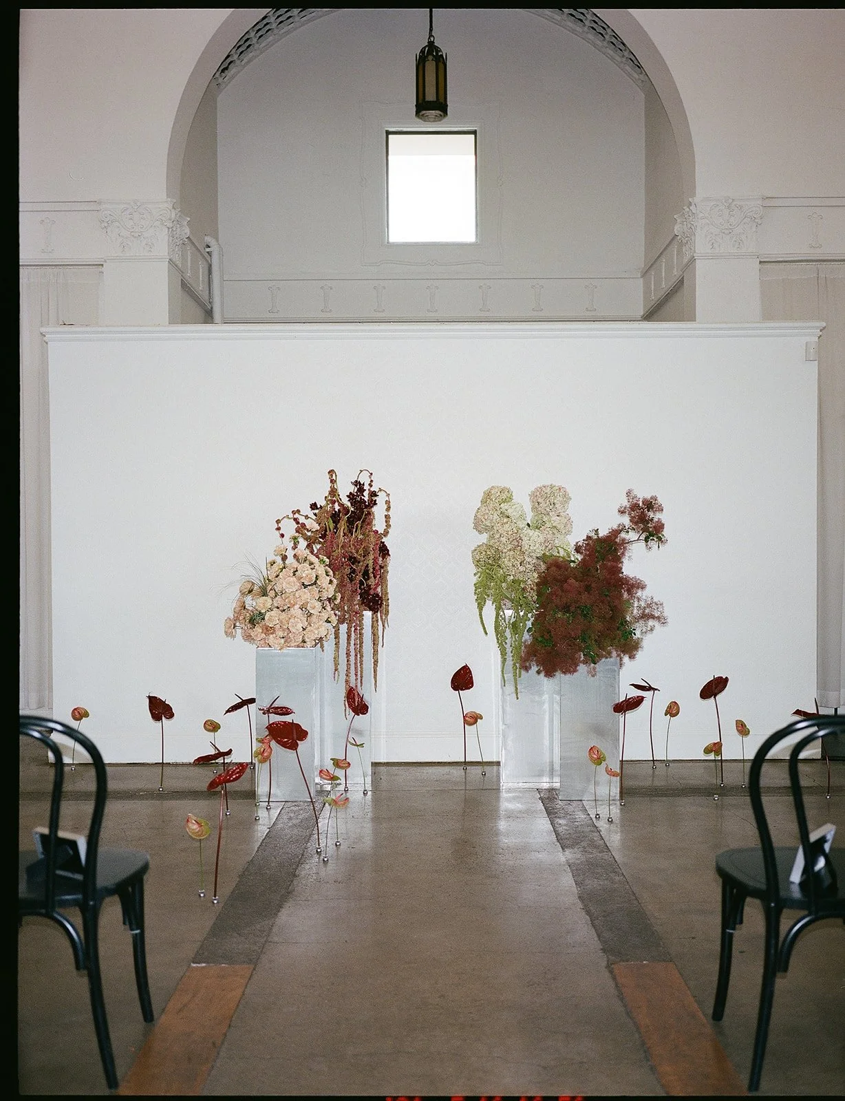Indoor wedding ceremony with colorful floral arrangements lining the aisle at La Villa in Kansas City.