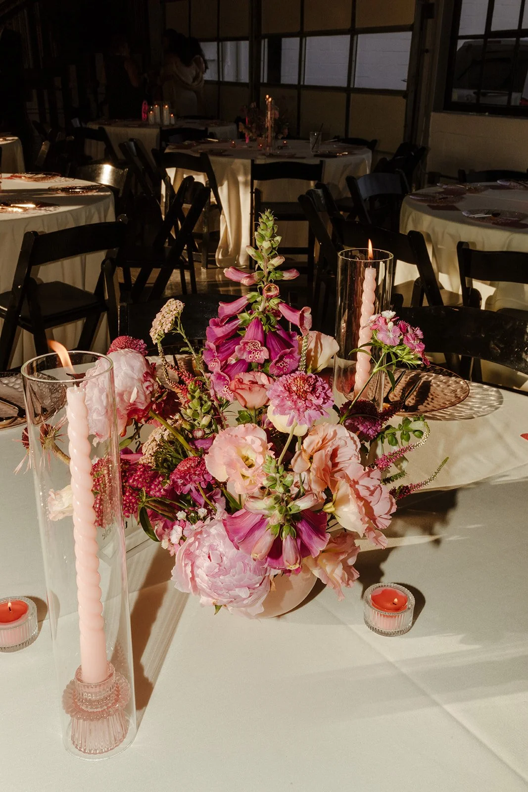 Pink wedding centerpiece with colorful florals and candlelight at The Delaware in Independence, Missouri.