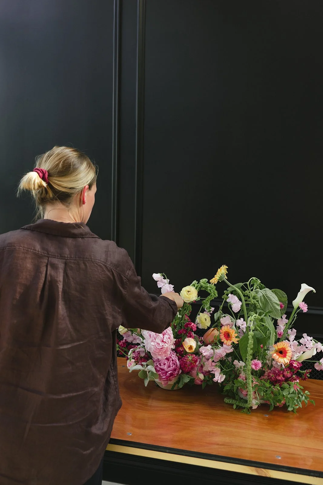 Saige of Elizabeth McKenzie Florals arranging a colorful wedding bouquet at The Glass House at River Oaks in Kansas City.