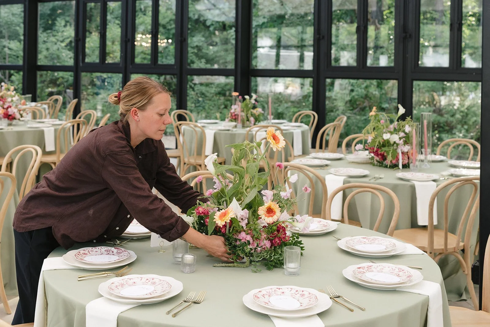 Elizabeth McKenzie Florals arranging wedding centerpieces at The Glass House at River Oaks in Kansas City.
