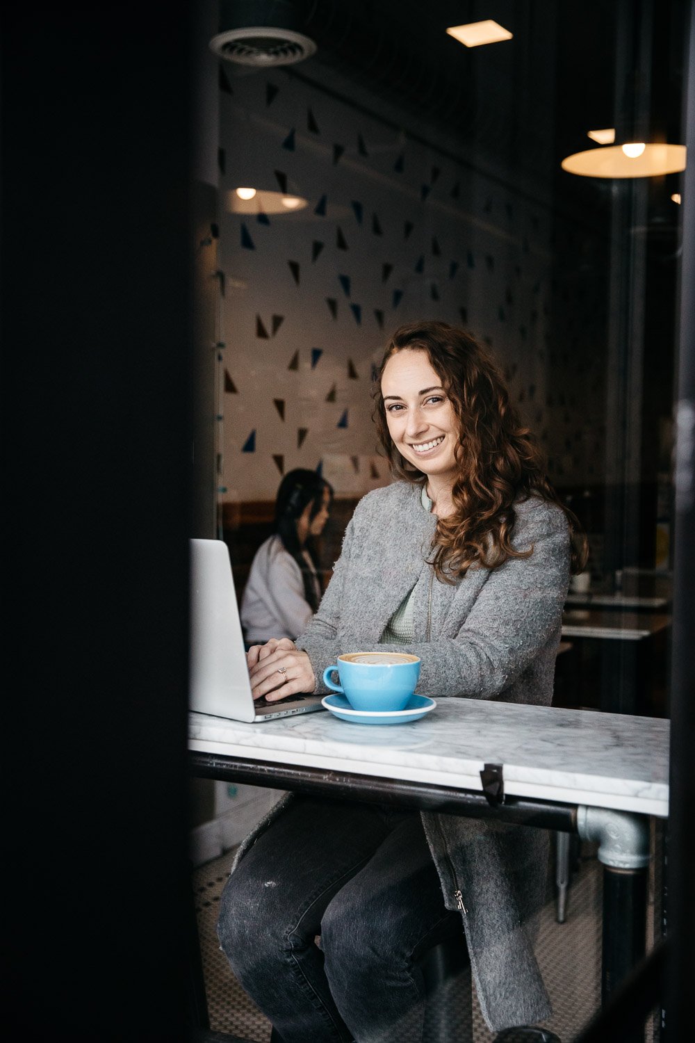  brand portrait shot through a window of smiling photographer Toni Toscano at Home Coffee Roasters, shot in San Francisco by brand photographer Allison Busch Photography 