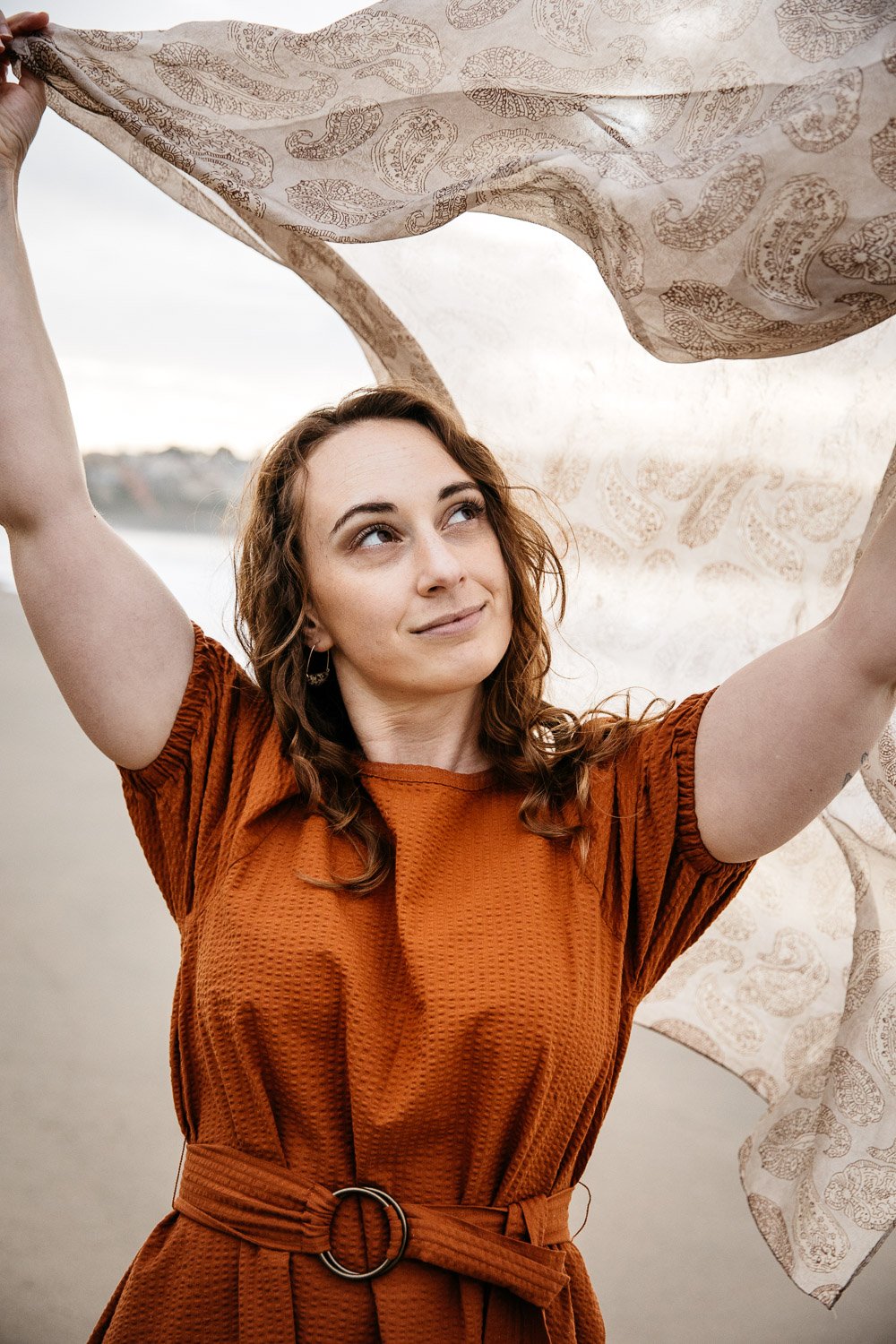  brand portrait of photographer Toni Toscano holding scarf in the wind with the ocean behind her, shot at Baker Beach in San Francisco by brand photographer Allison Busch Photography 