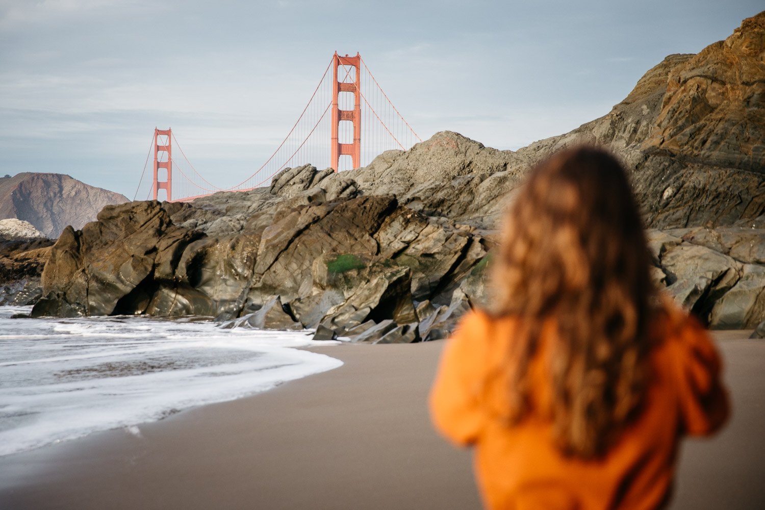  brand portrait of photographer Toni Toscano taking a photograph of the Golden Gate Bridge which looms in the background, shot at Baker Beach in San Francisco by brand photographer Allison Busch Photography 