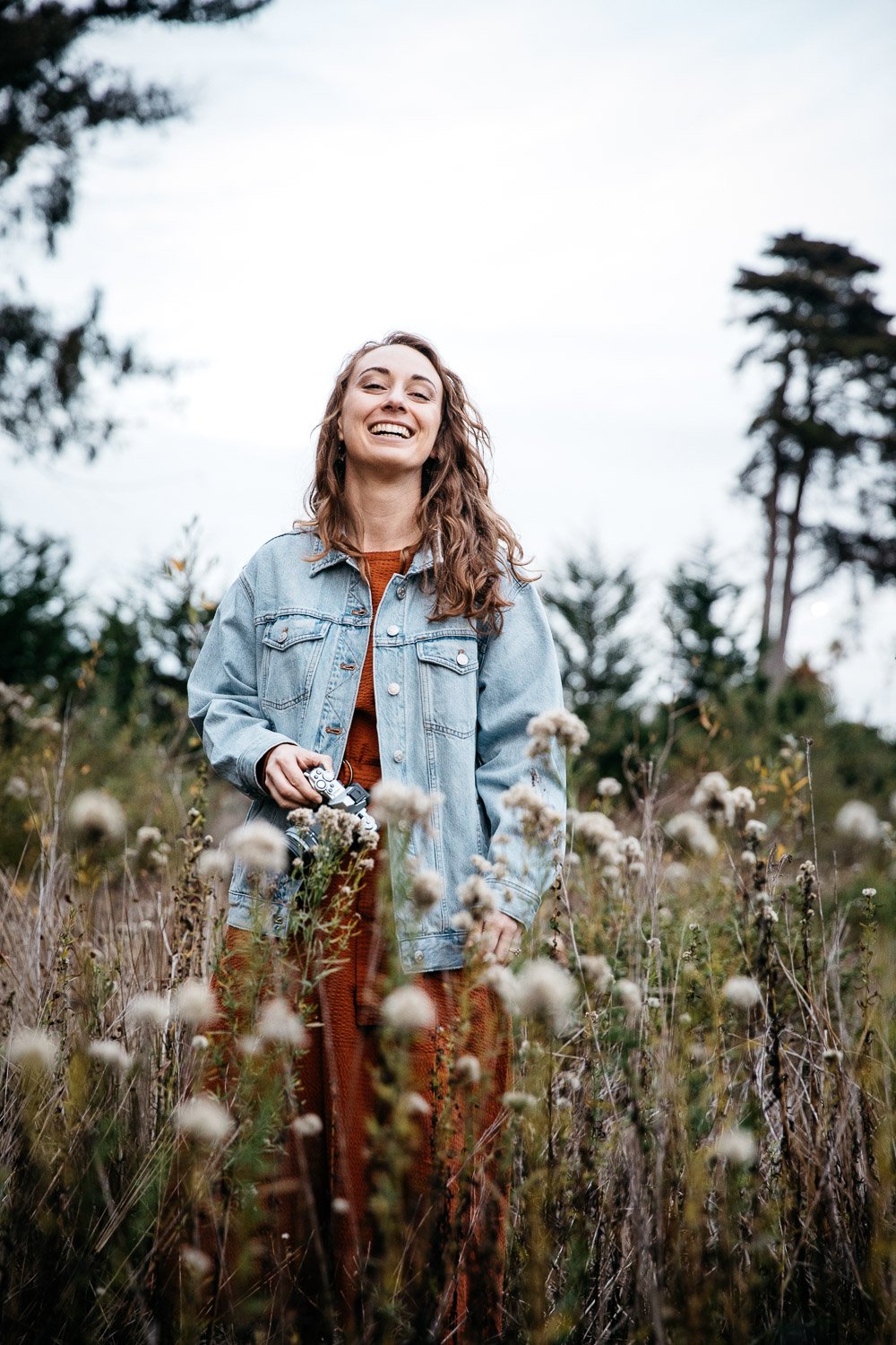  brand portrait of photographer Toni Toscano holding her camera in a meadow of wildflowers at sunset, shot in the Presidio in San Francisco by brand photographer Allison Busch Photography 