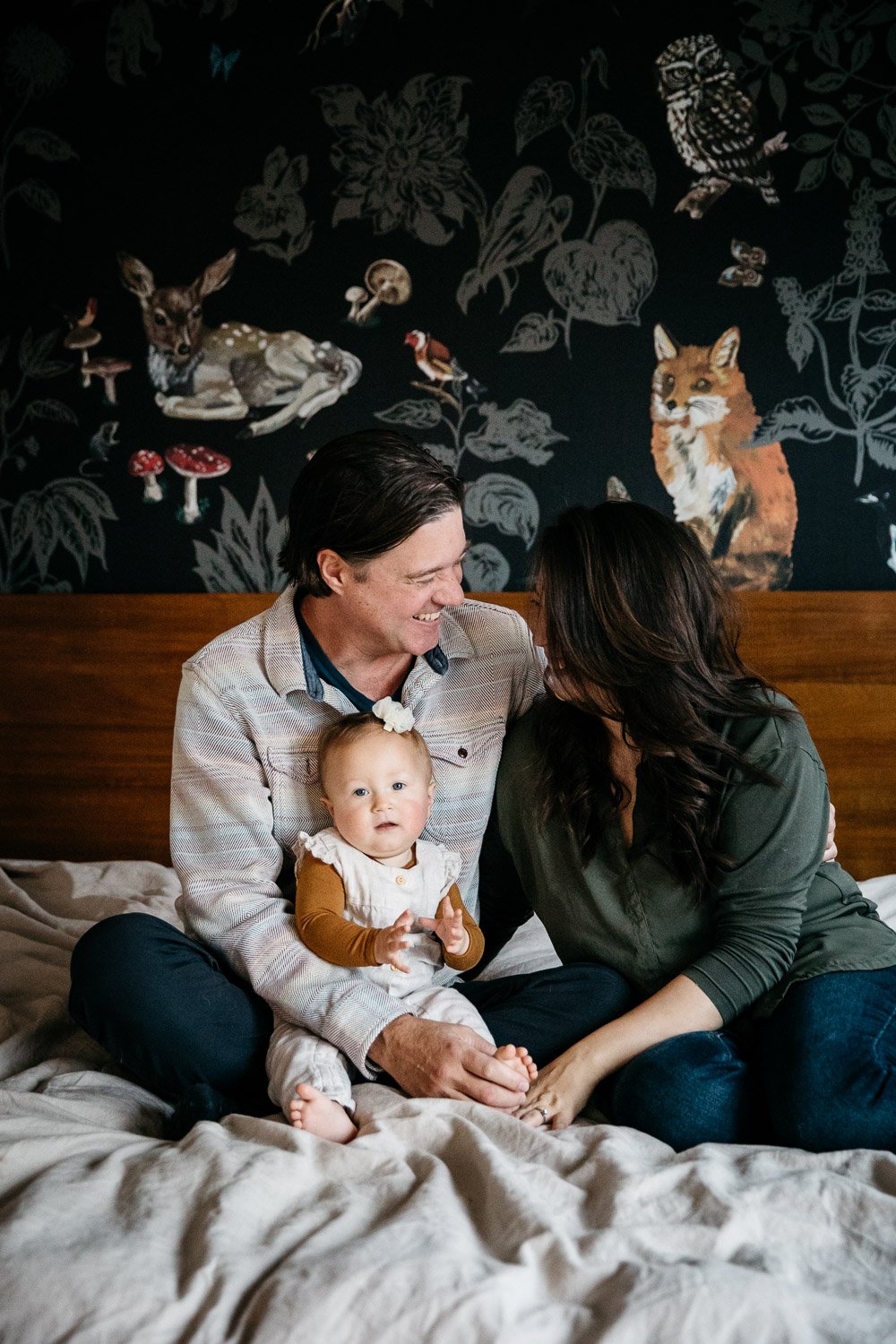  family photograph of mom, dad, and baby at home in bed with soft light and fun wallpaper, shot in Berkeley by family photographer Allison Busch Photography 