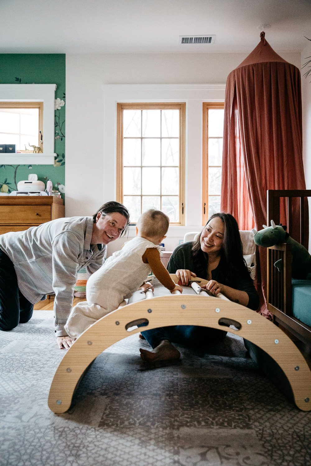  family photograph of mom, dad, and baby at home with green wallpaper and pink canopy, shot in Berkeley by family photographer Allison Busch Photography 