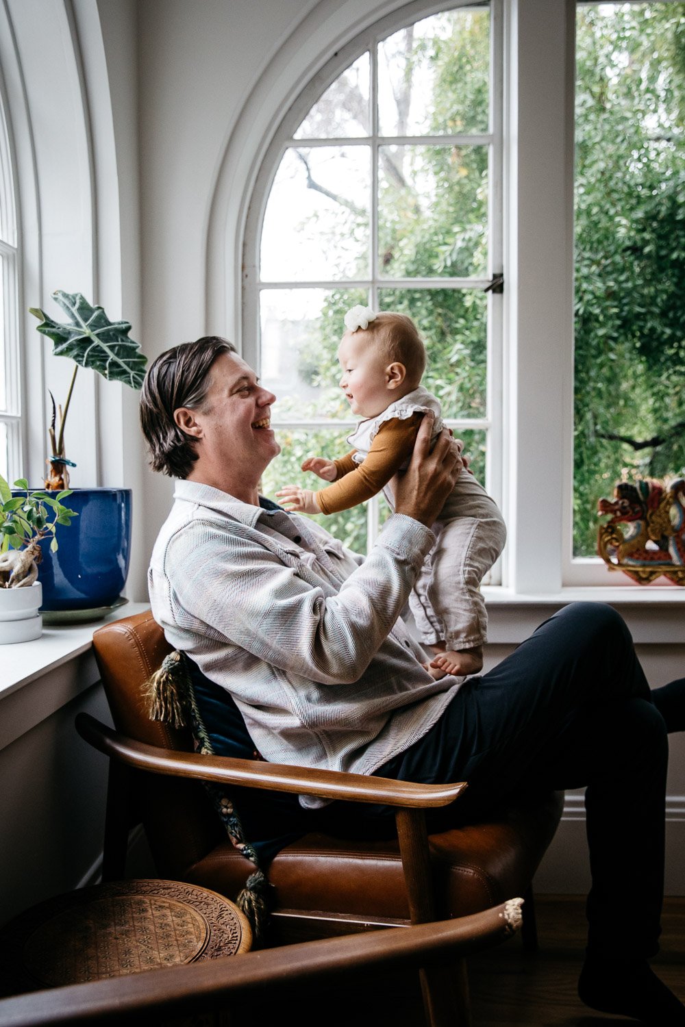  family photograph of dad and baby at home and sitting in chair next to windows in light-filled room, shot in Berkeley by family photographer Allison Busch Photography 