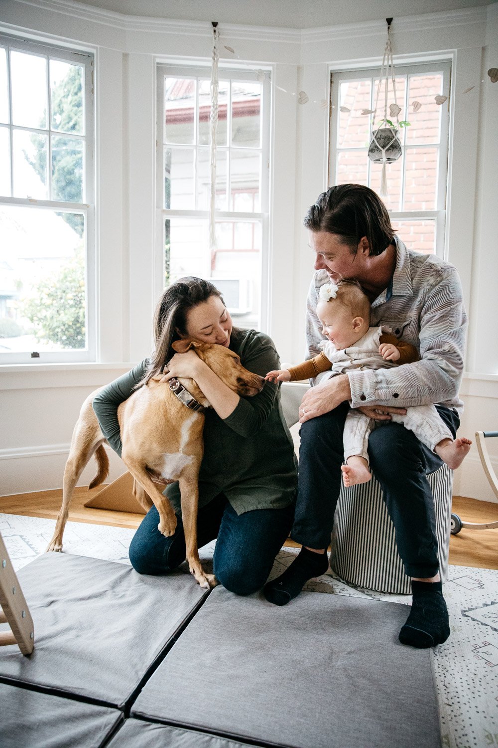  family photograph of mom, dad, and baby at home and sitting on floor in light-filled room with dog, shot in Berkeley by family photographer Allison Busch Photography 